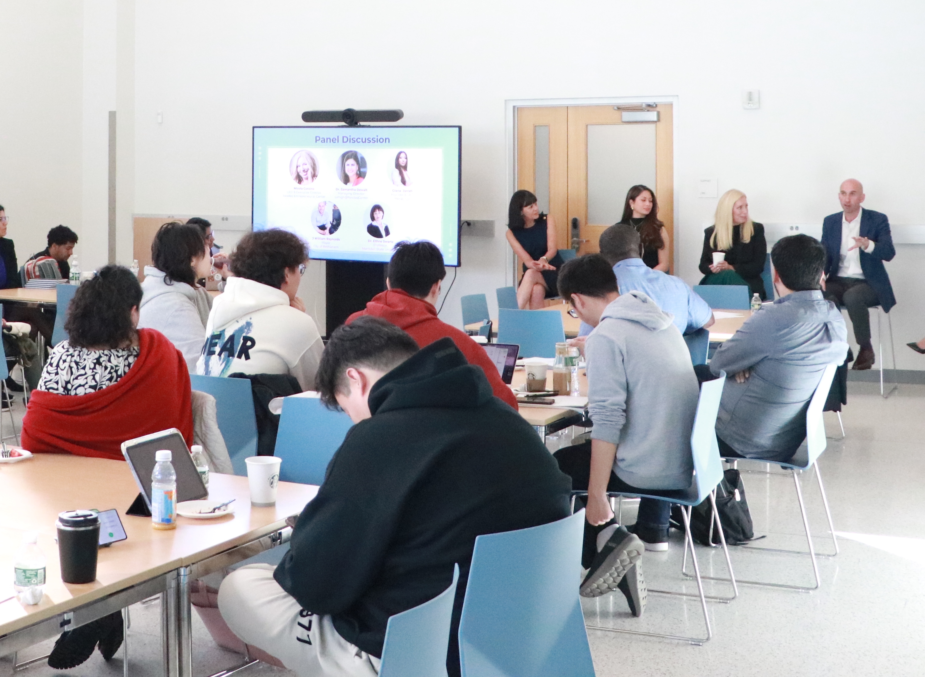 People gathered at tables for a panel discussion event