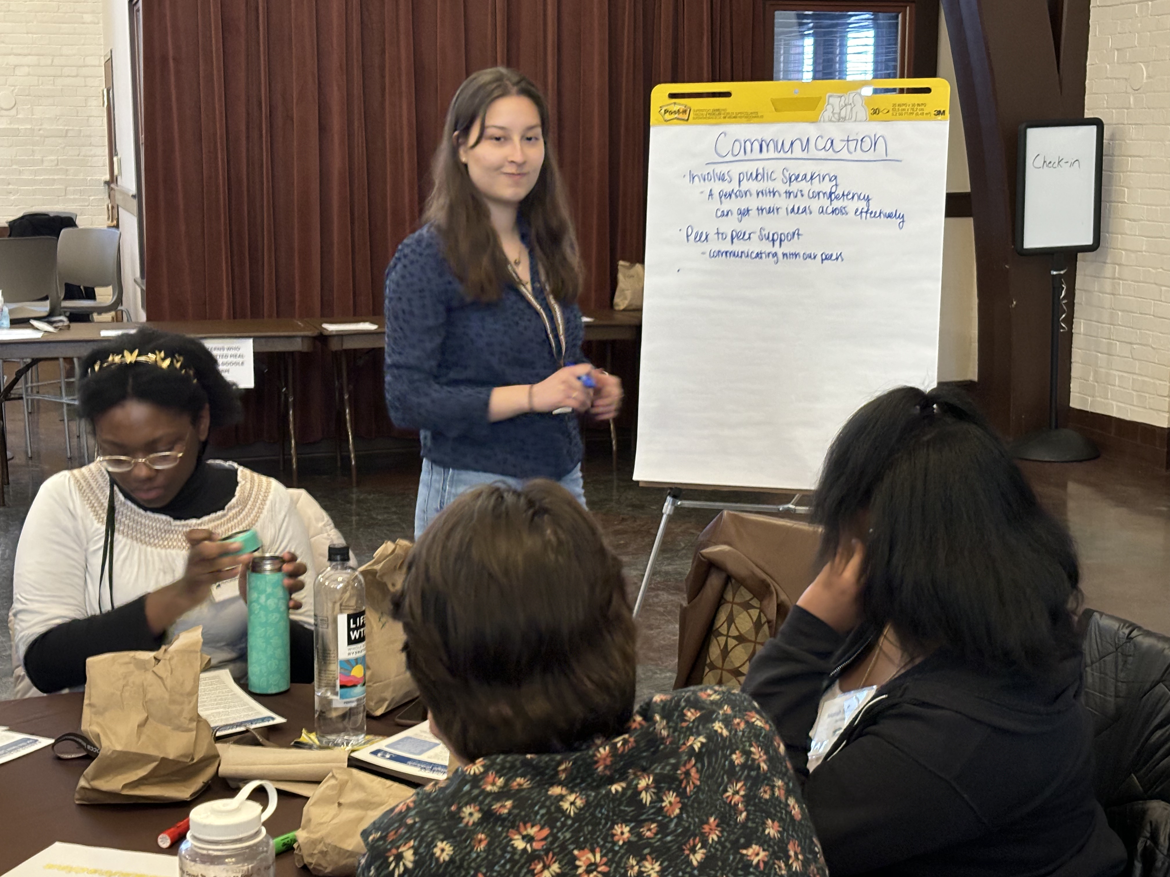 Lehigh University students talking while writing about communications on an easel