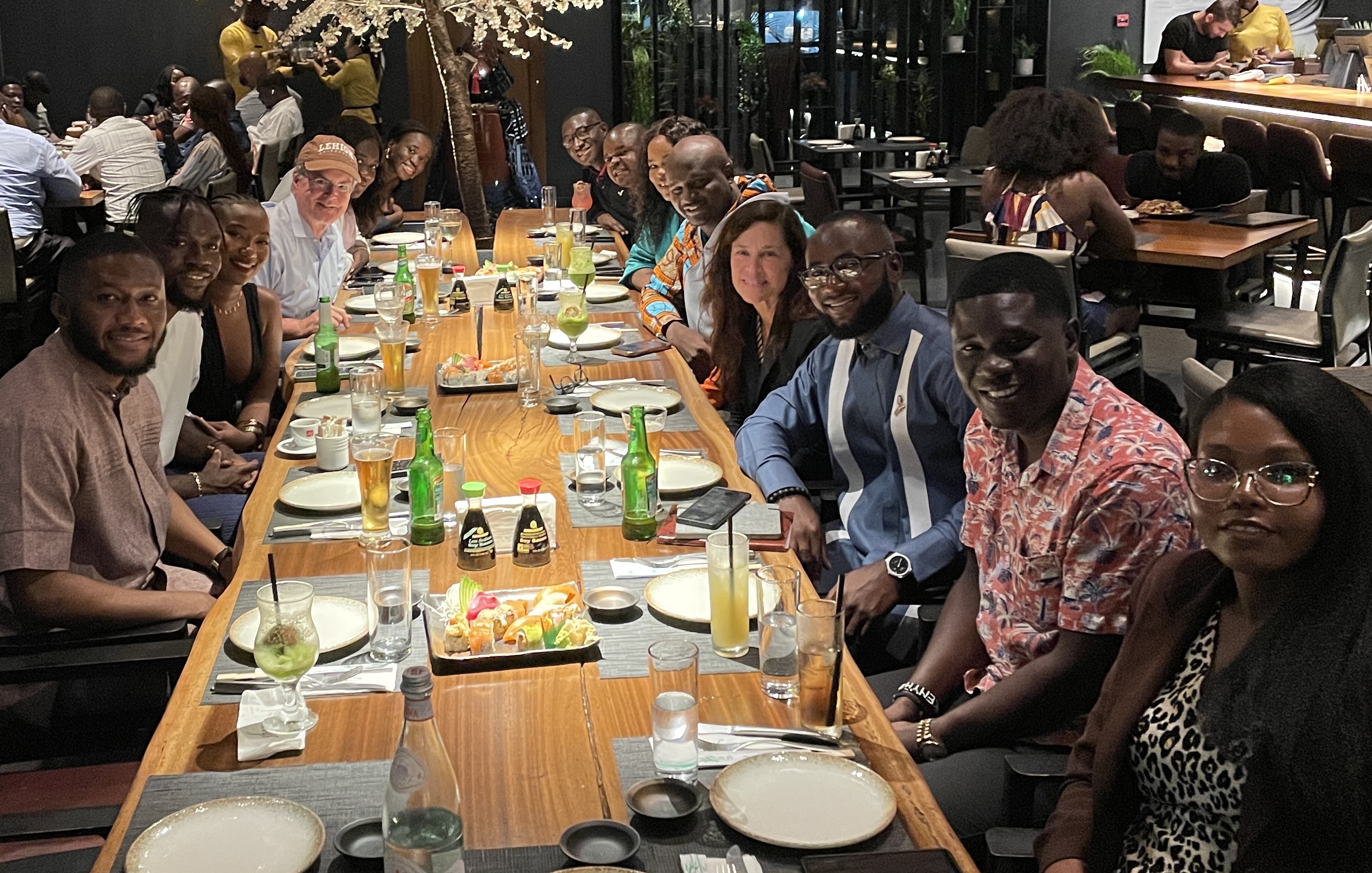 Several people sitting at a table in a restaurant, smiling for the camera