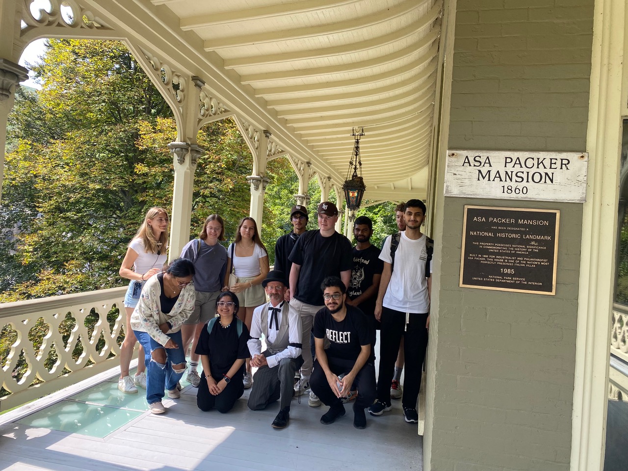 A group of college students standing on the front deck of Asa Packer Mansion