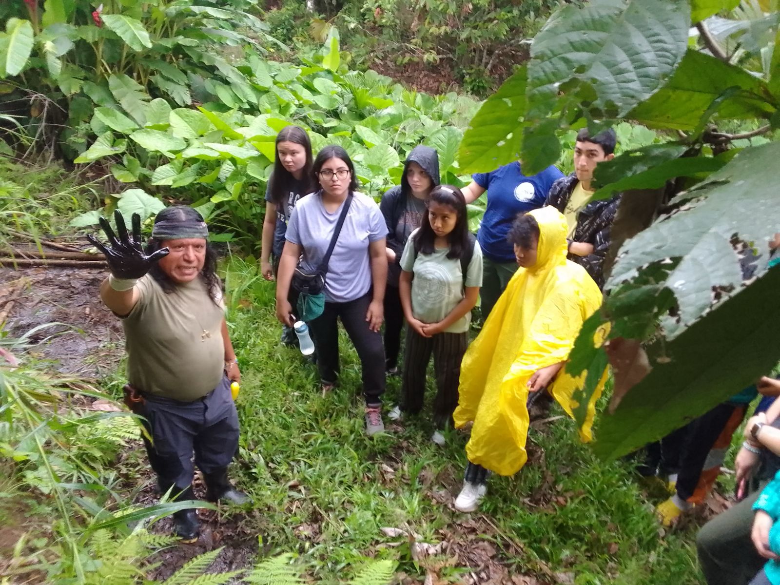 Students listening to a teacher pointing up at a tree in the Amazon rain forest