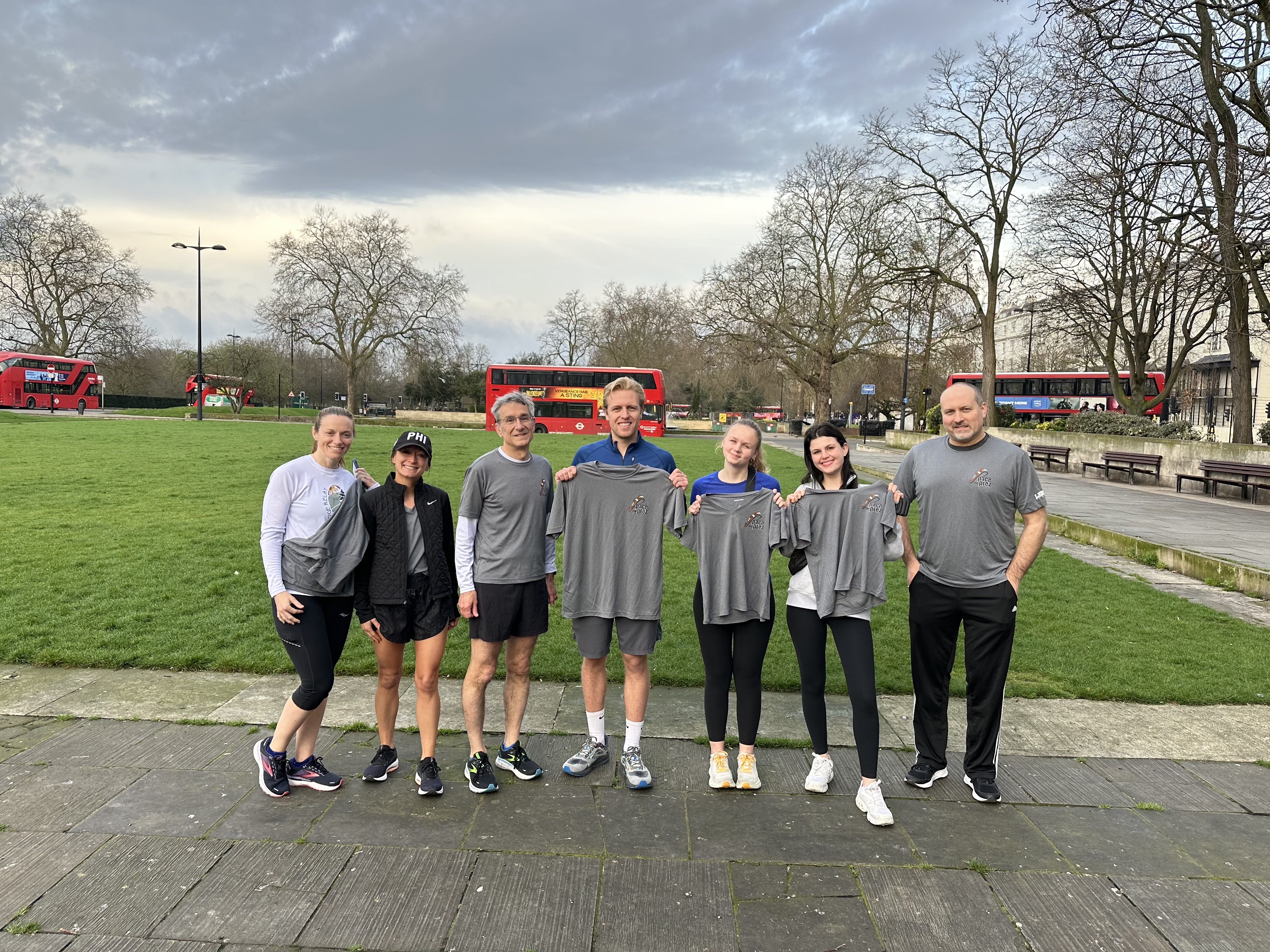 Lehigh University community members standing in a park holding or wearing grey running shirts