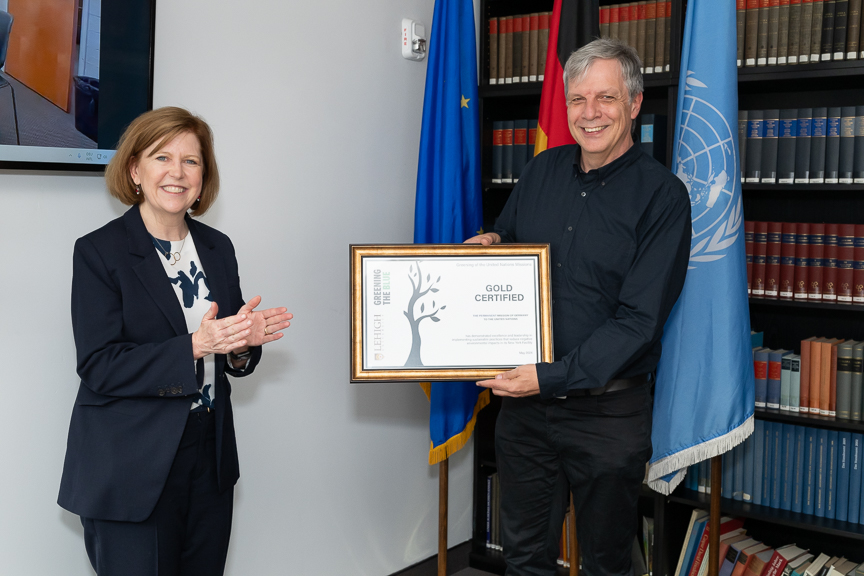 Two people holding a certification at the German Mission of the United Nations