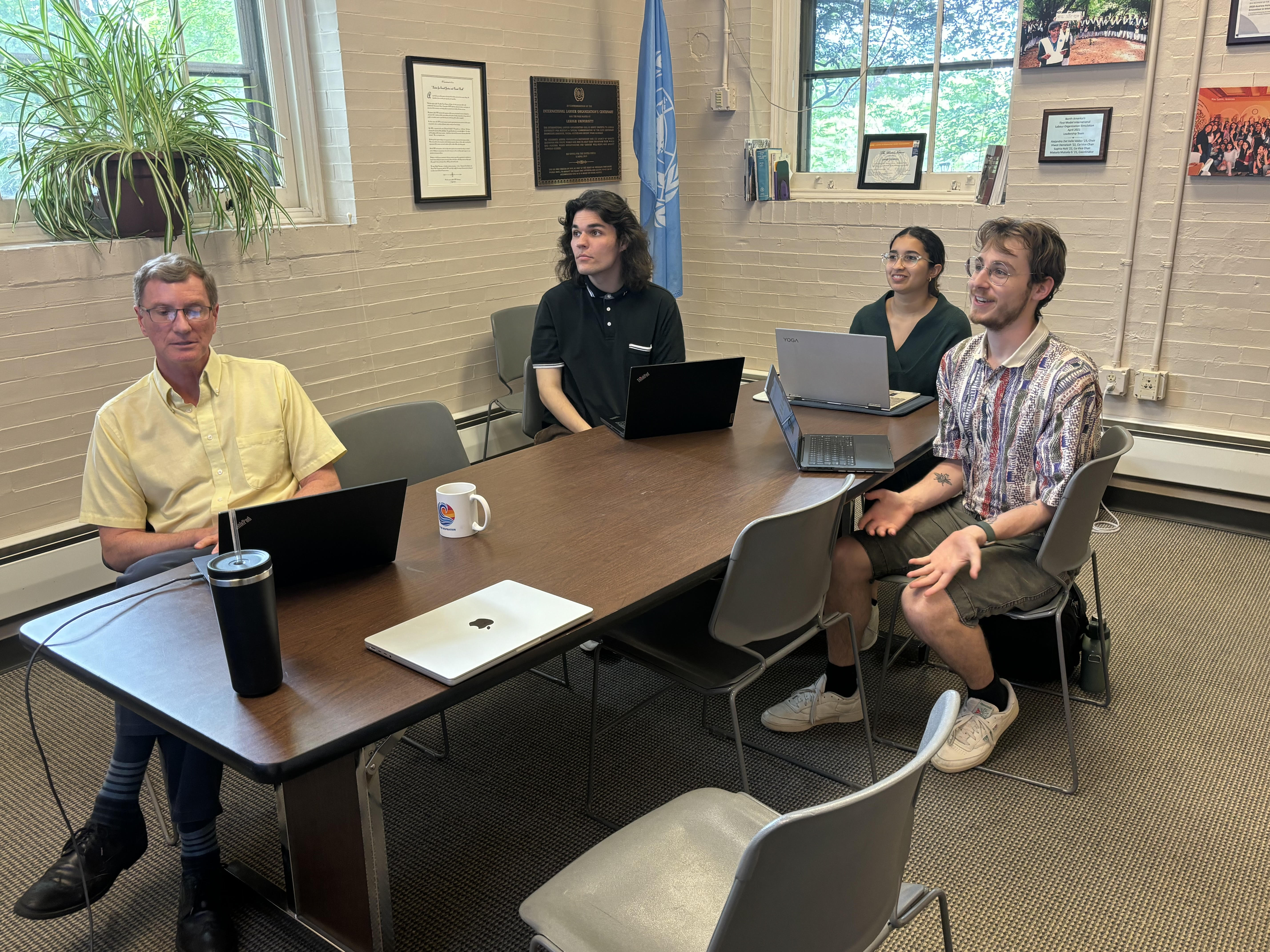 Four people watching a video screen in a conference room