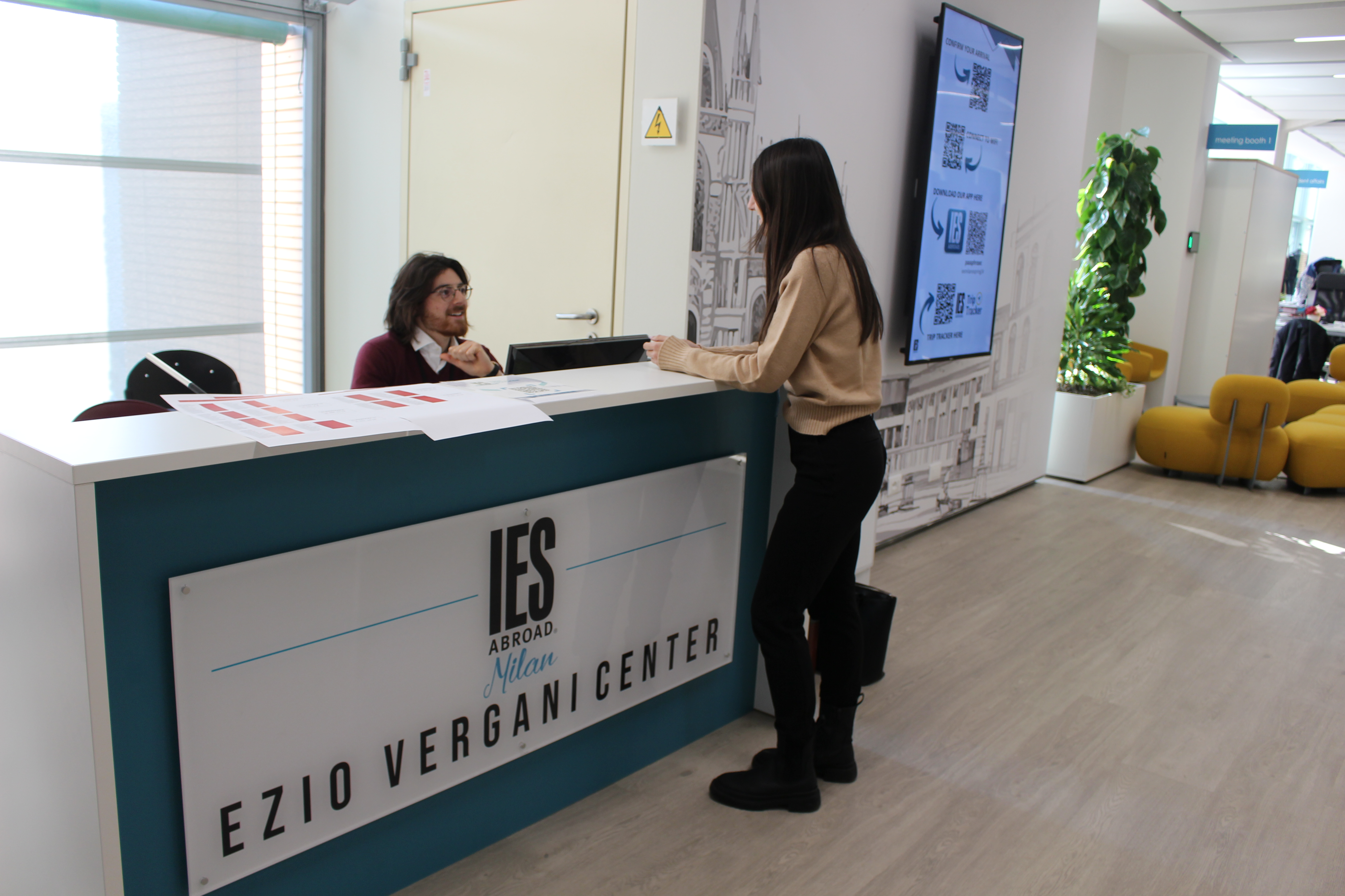 A student talking to a person at the front desk at the IES Abroad Milan Center