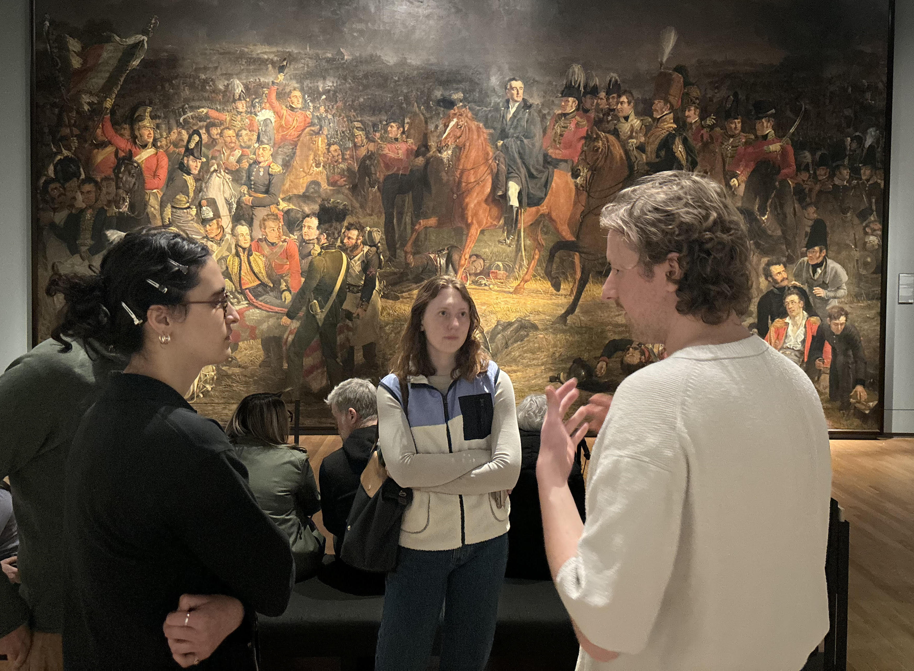 A professor talking to students at the Rijksmusem in front of a painting