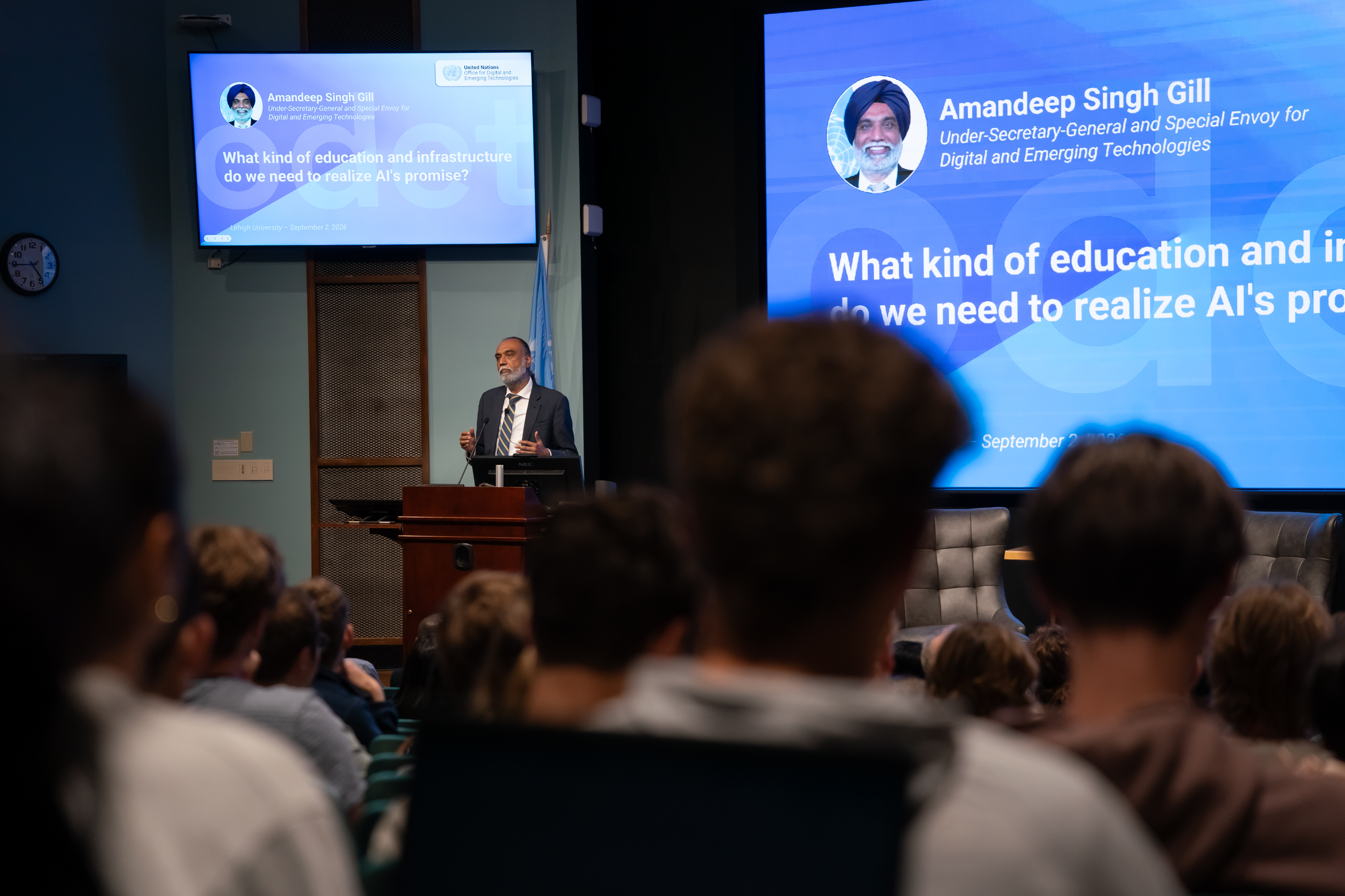 A man speaking a podium to an auditorium full of students