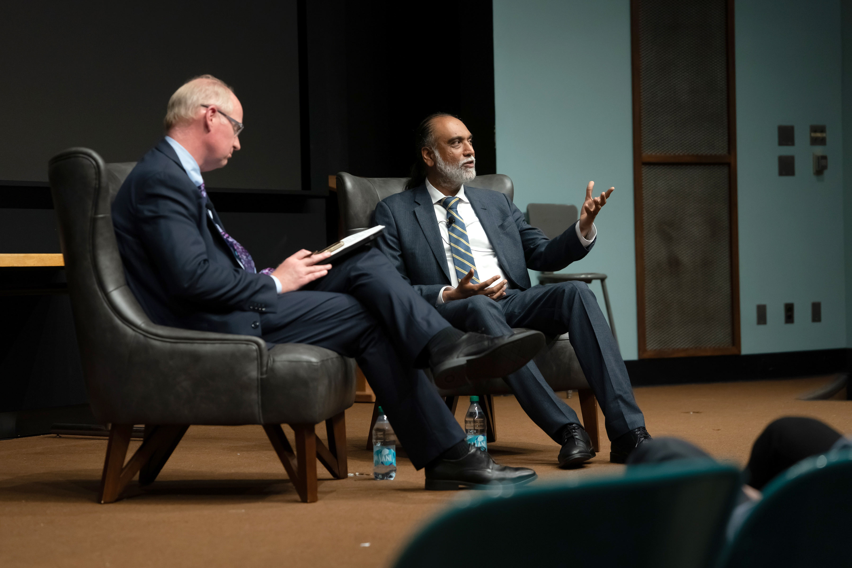 Two people sitting on chairs on a stage