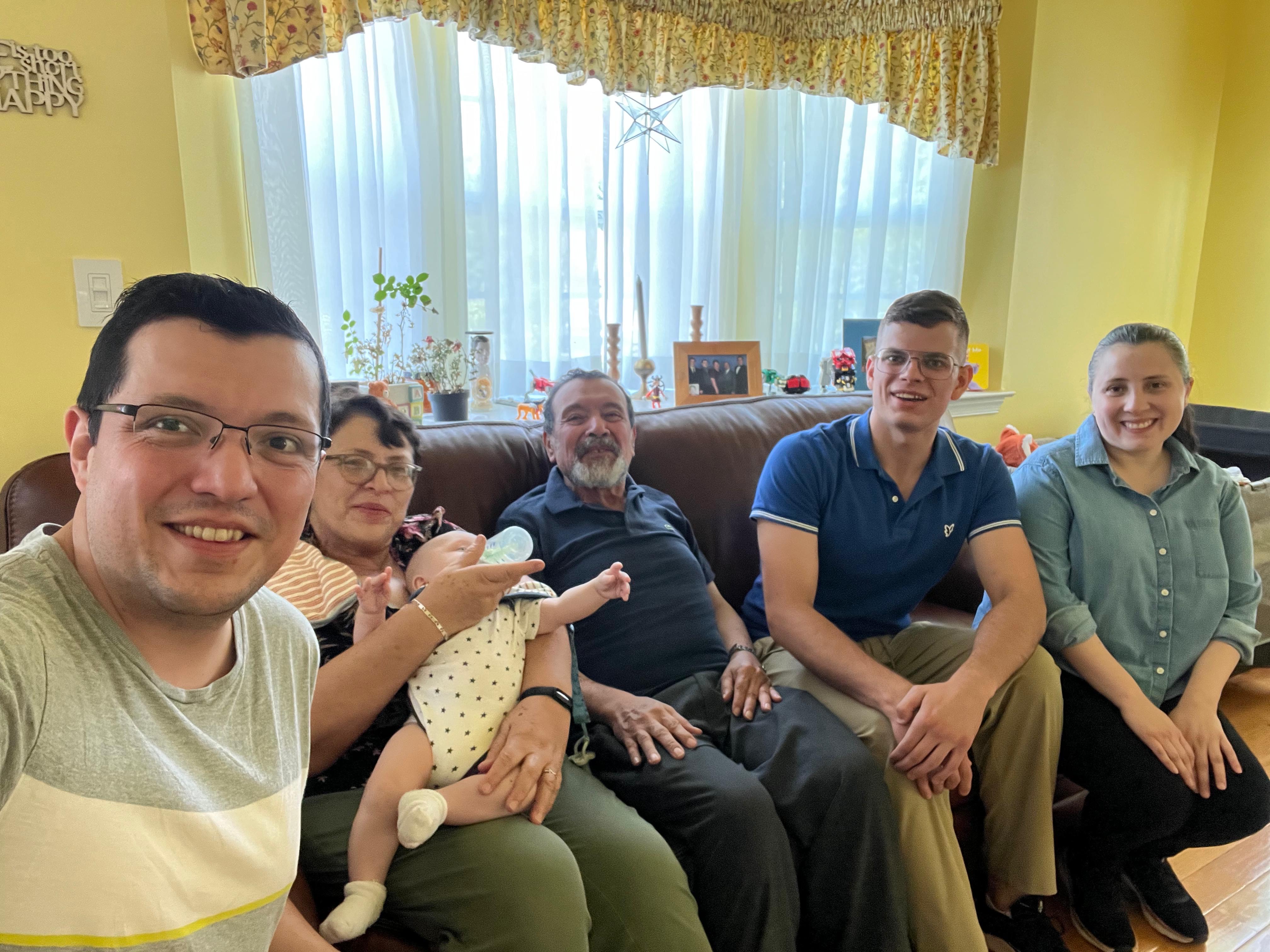 Several people sitting on a couch and smiling for the camera