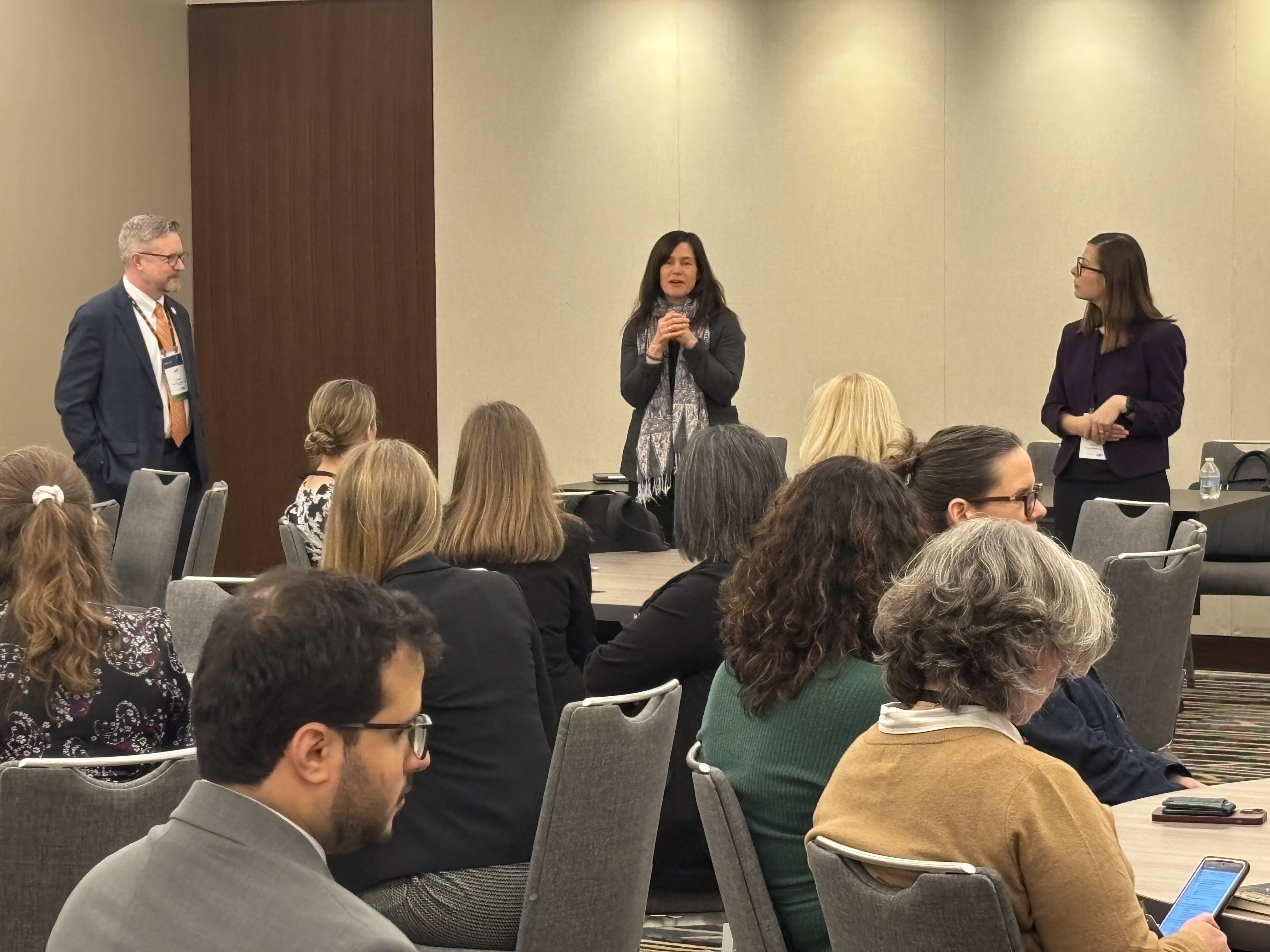 Three people speaking at a conference