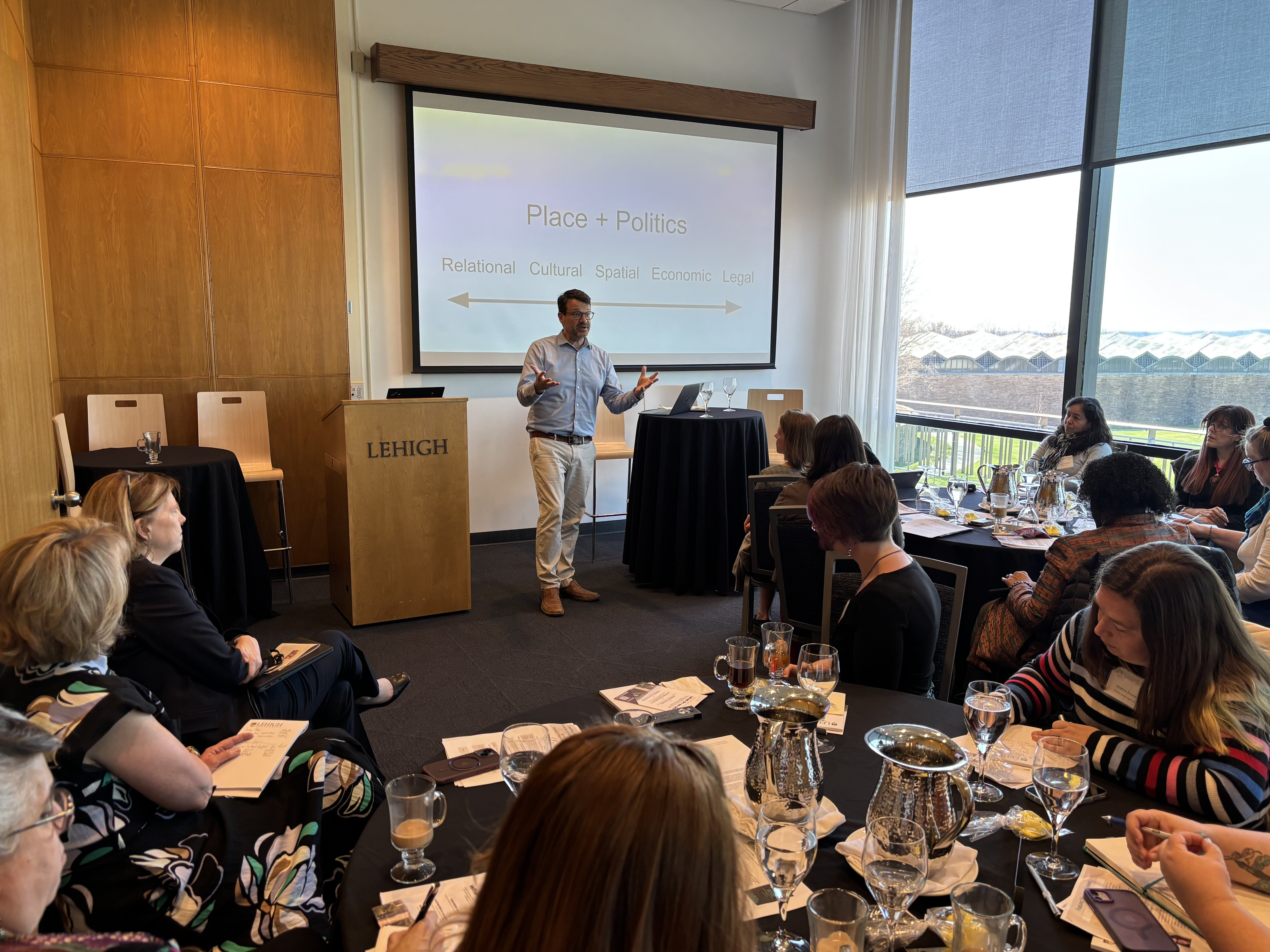 A man spoeaking in front of a PowerPoint presentation to a group of people