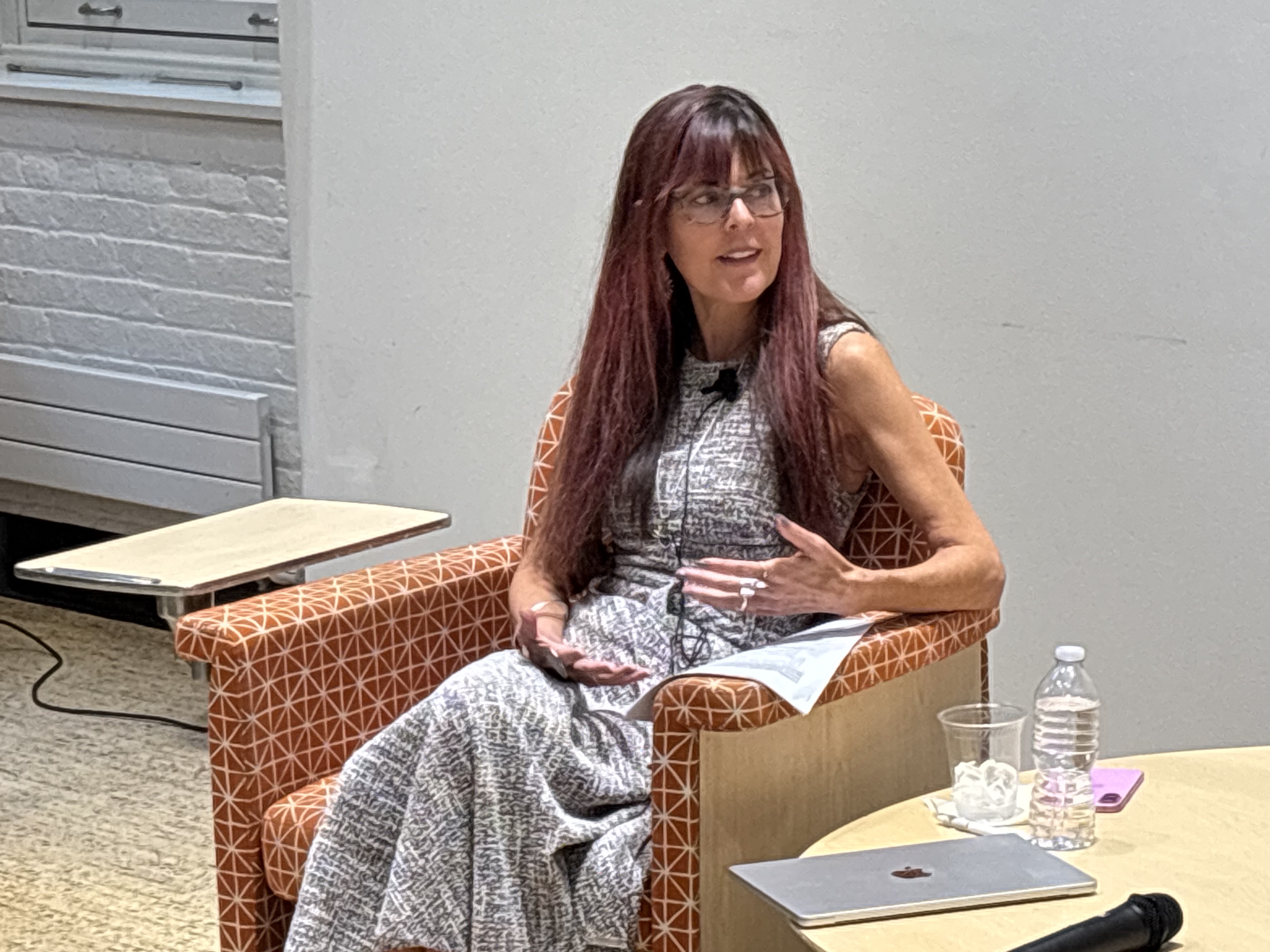 A woman sitting at a chair and speaking to someone off-camera