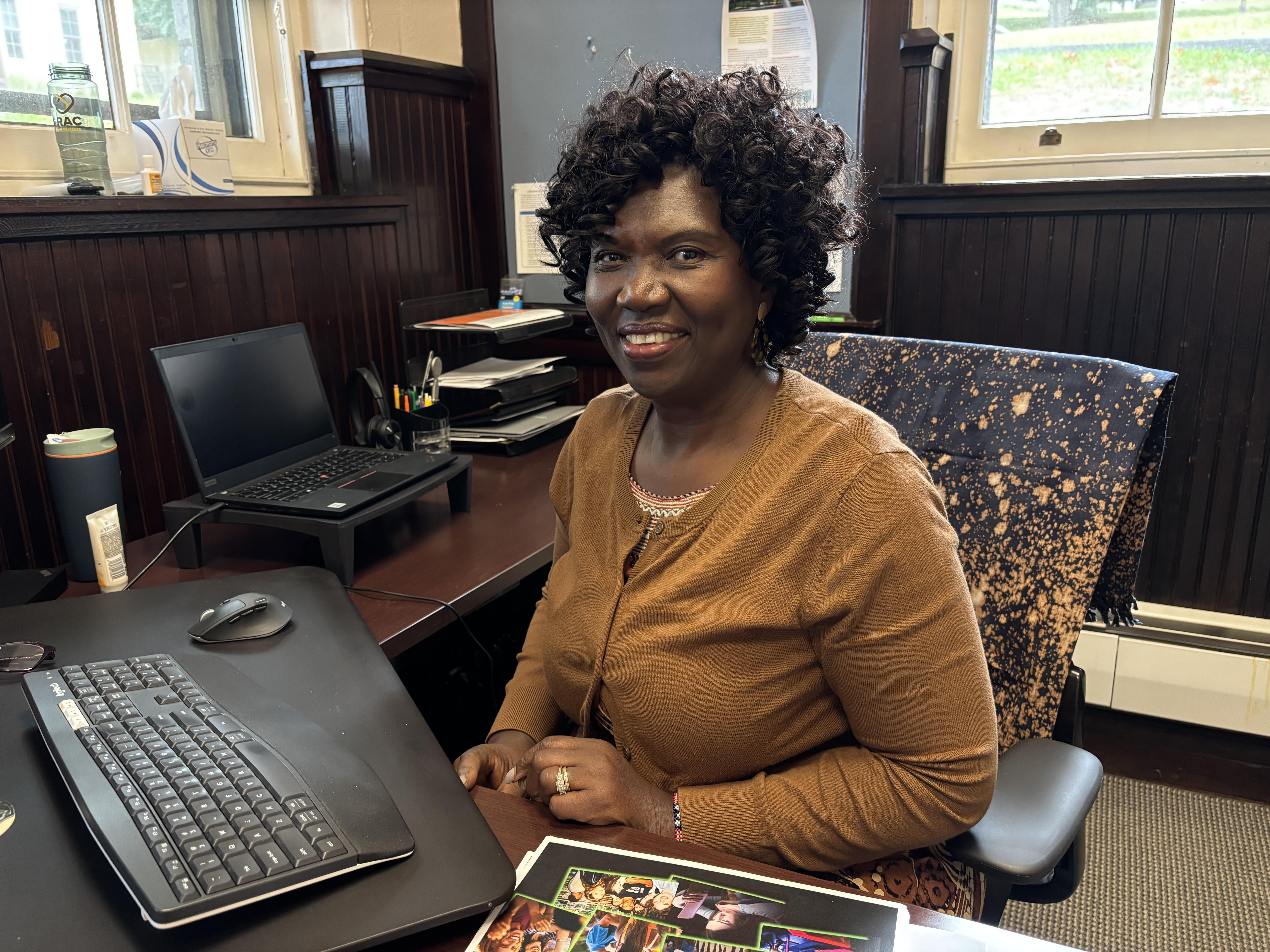 Asenath Asha Lutabingwa sitting at her computer desk