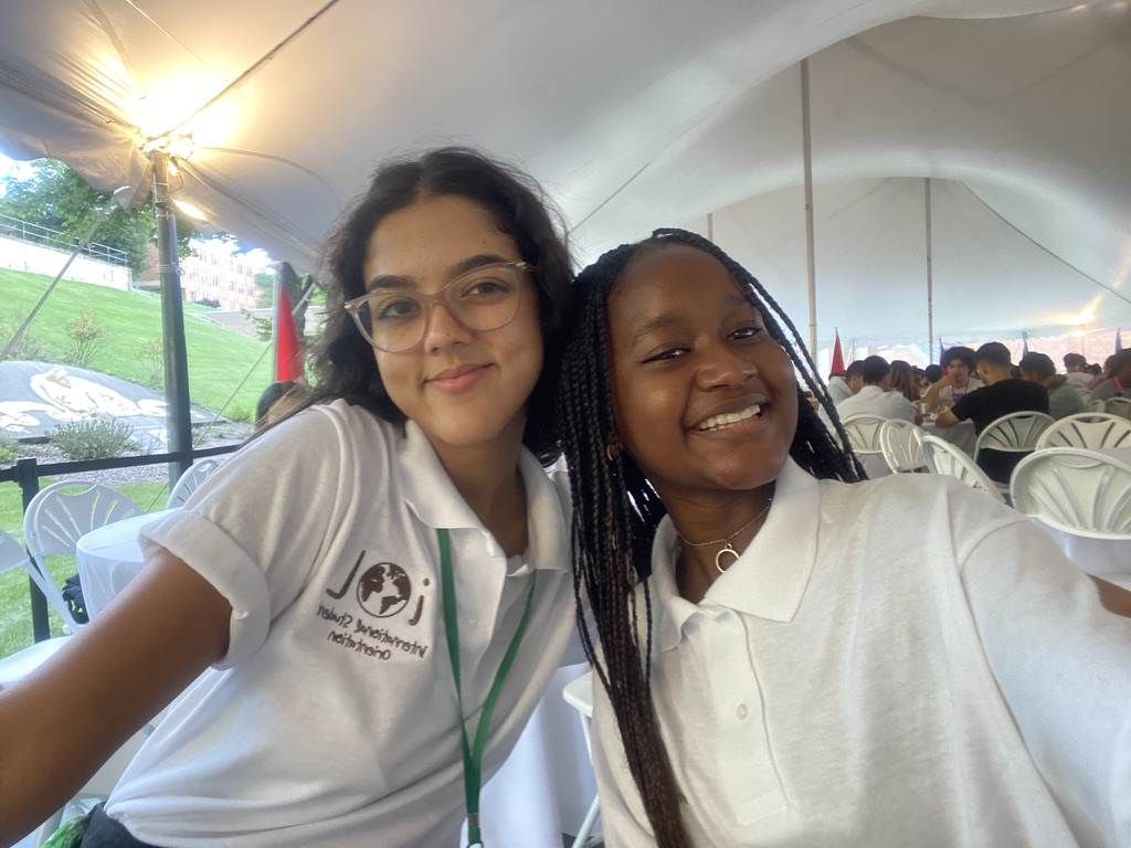 Two young women in white shirts pose for a selfie