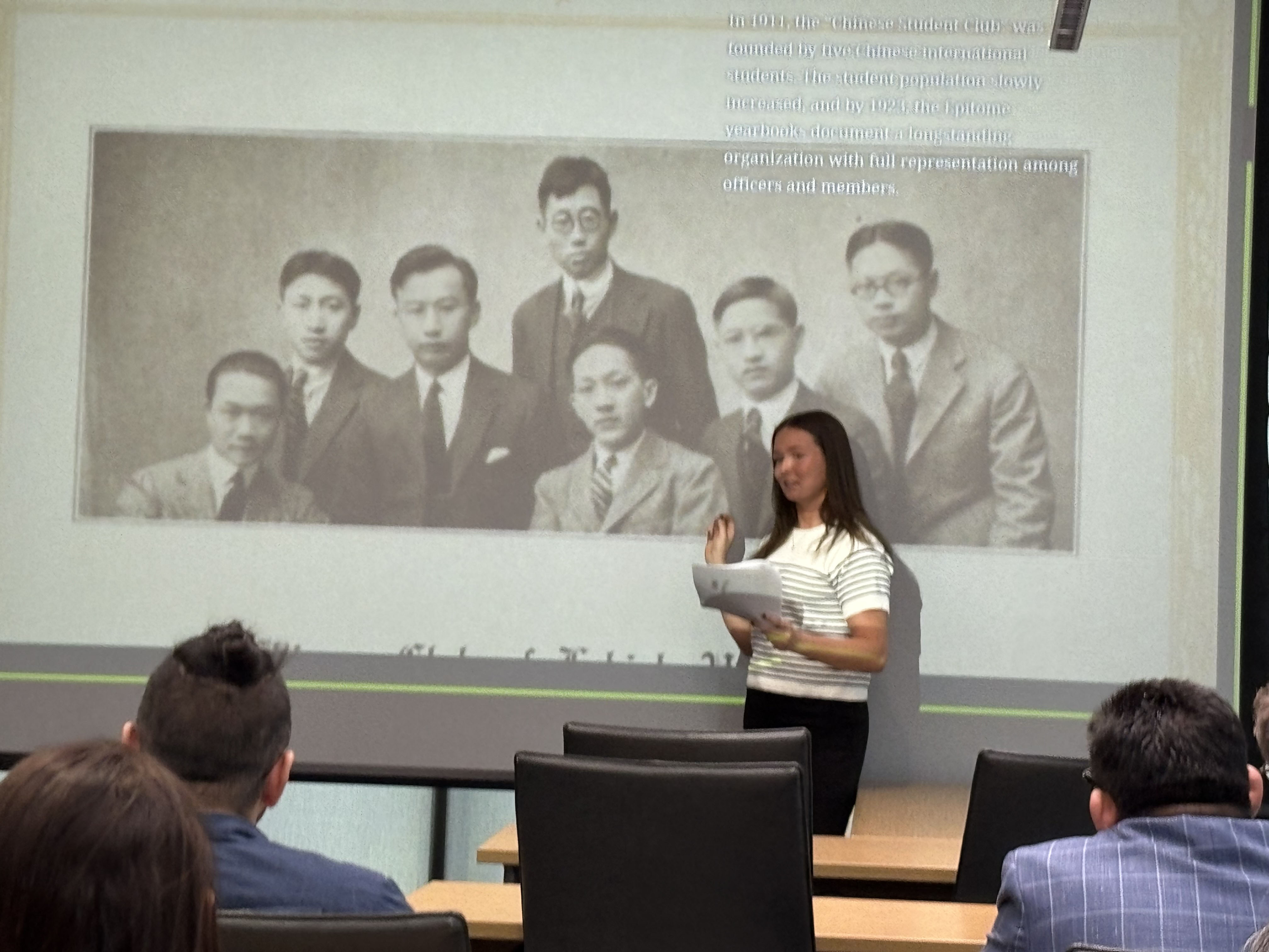 A young woman presenting in front of a powerpoint screen