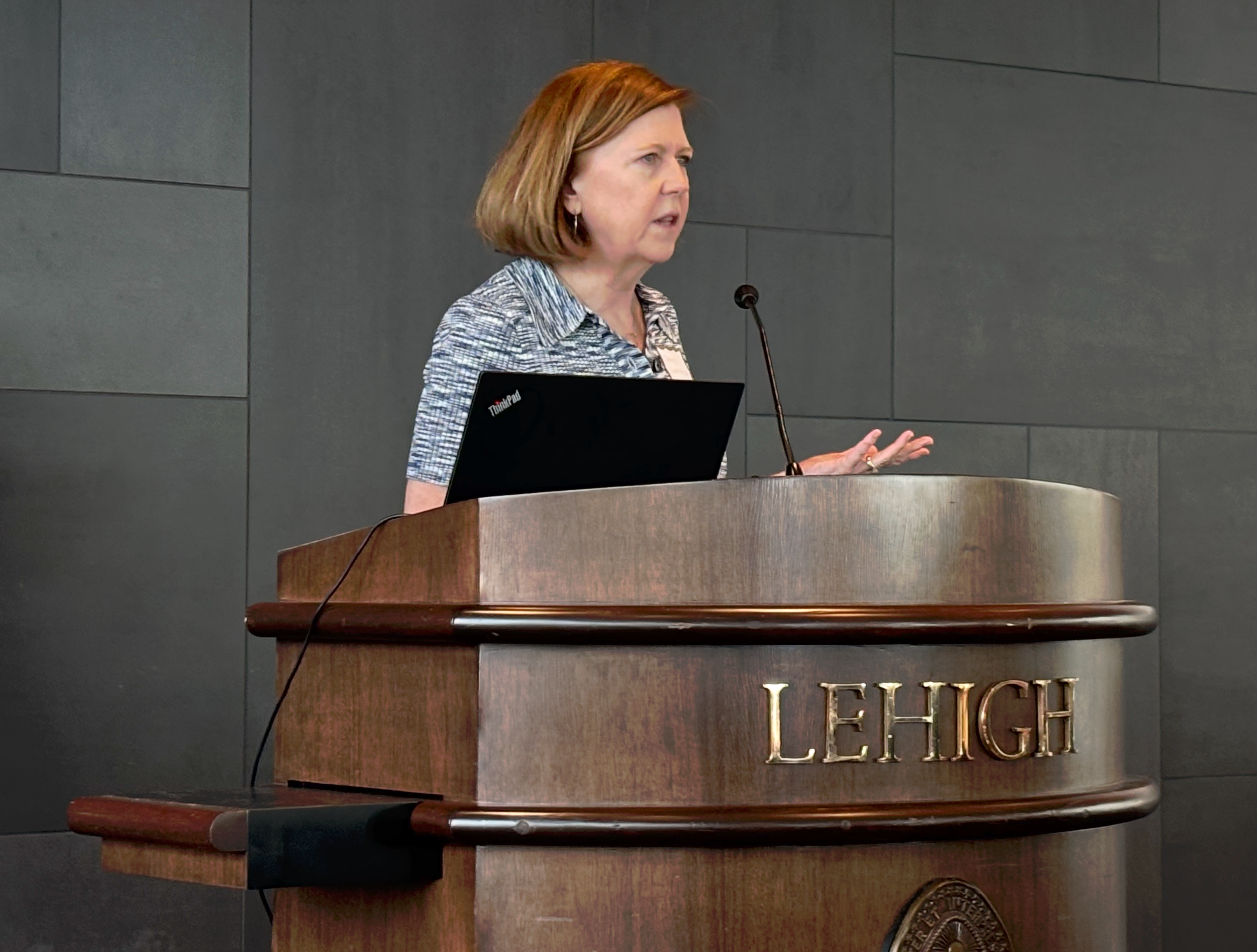 A woman speaking at a large podium that says Lehigh on the front
