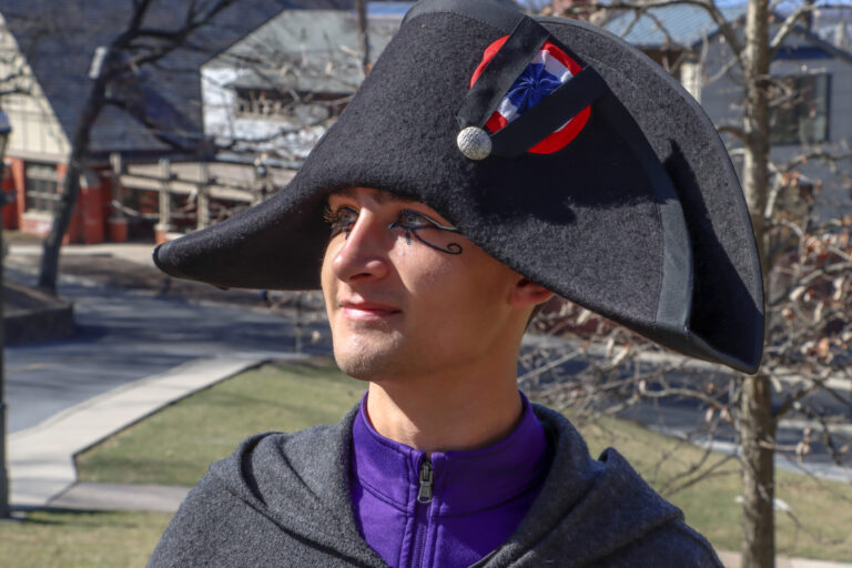 A young man wearing a Napoleon hat and eyeliner