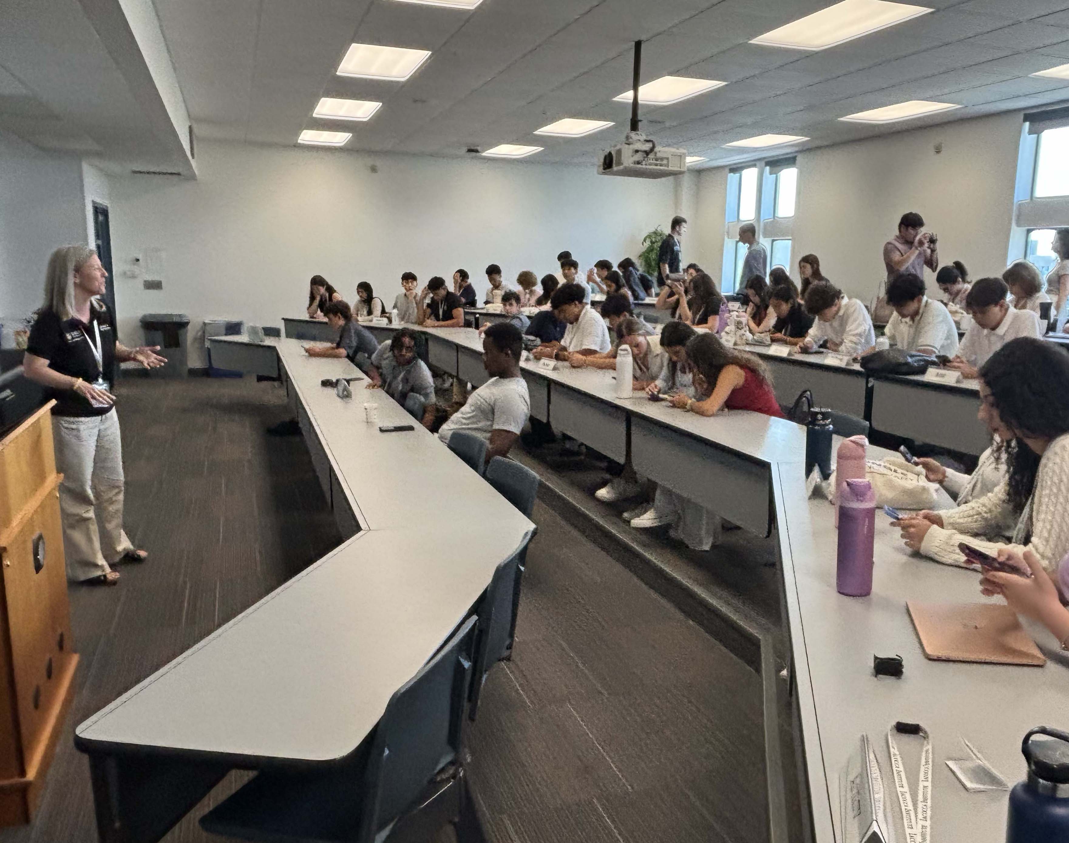A woman speaking to a group of students in a large classroom