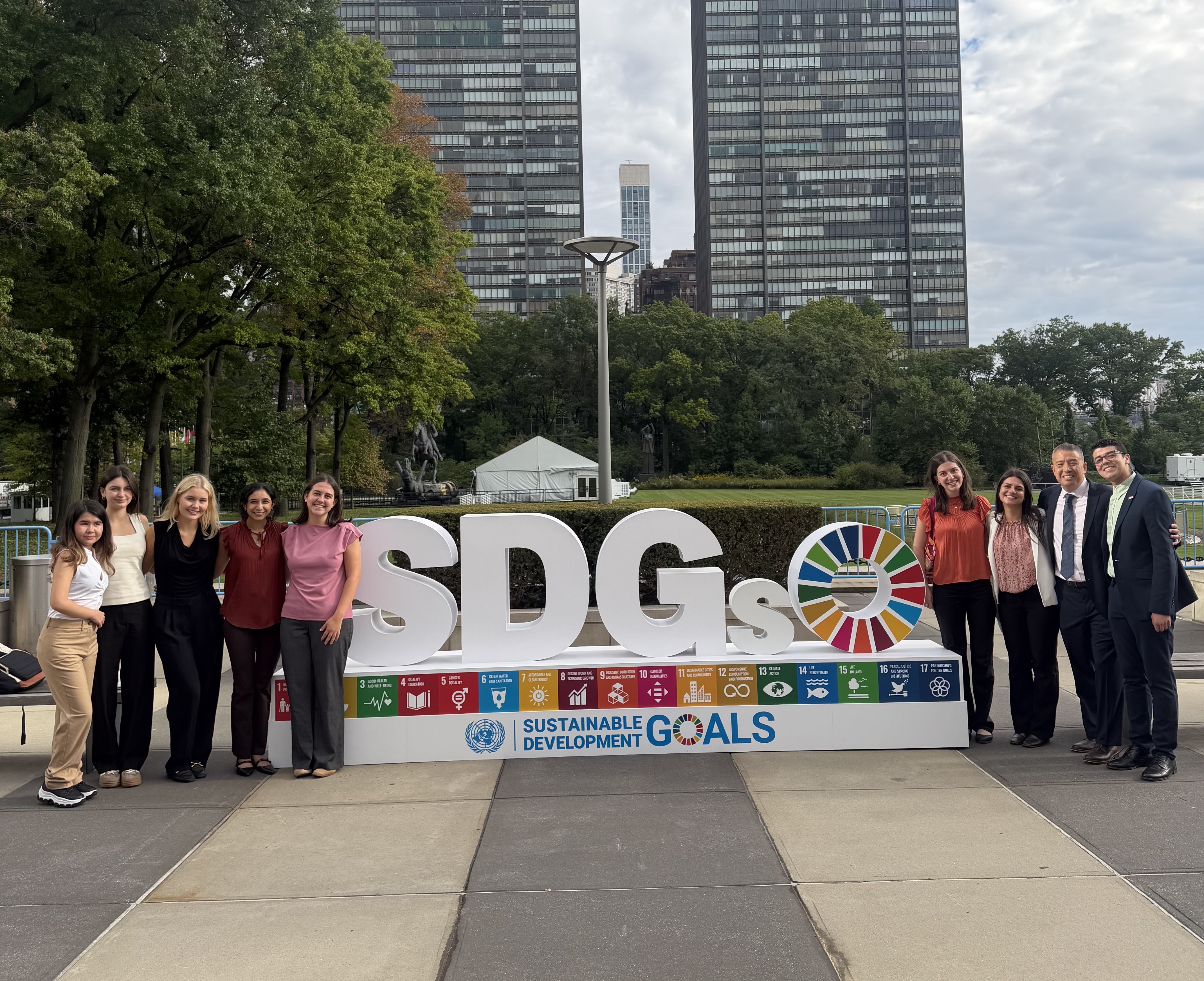 A gorup of people standing in front of a sign that says SDGs