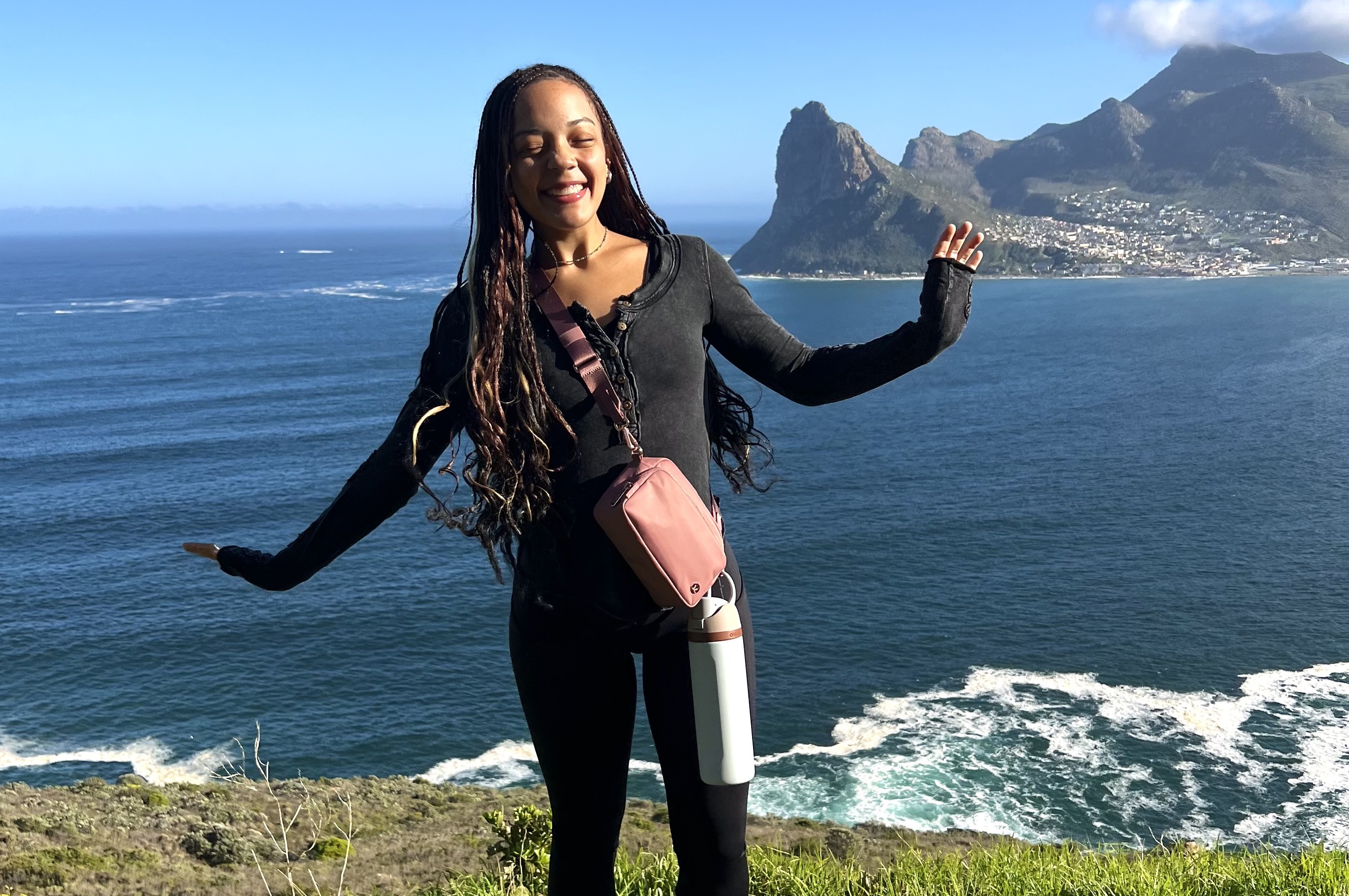 A woman posing on a grassy hill