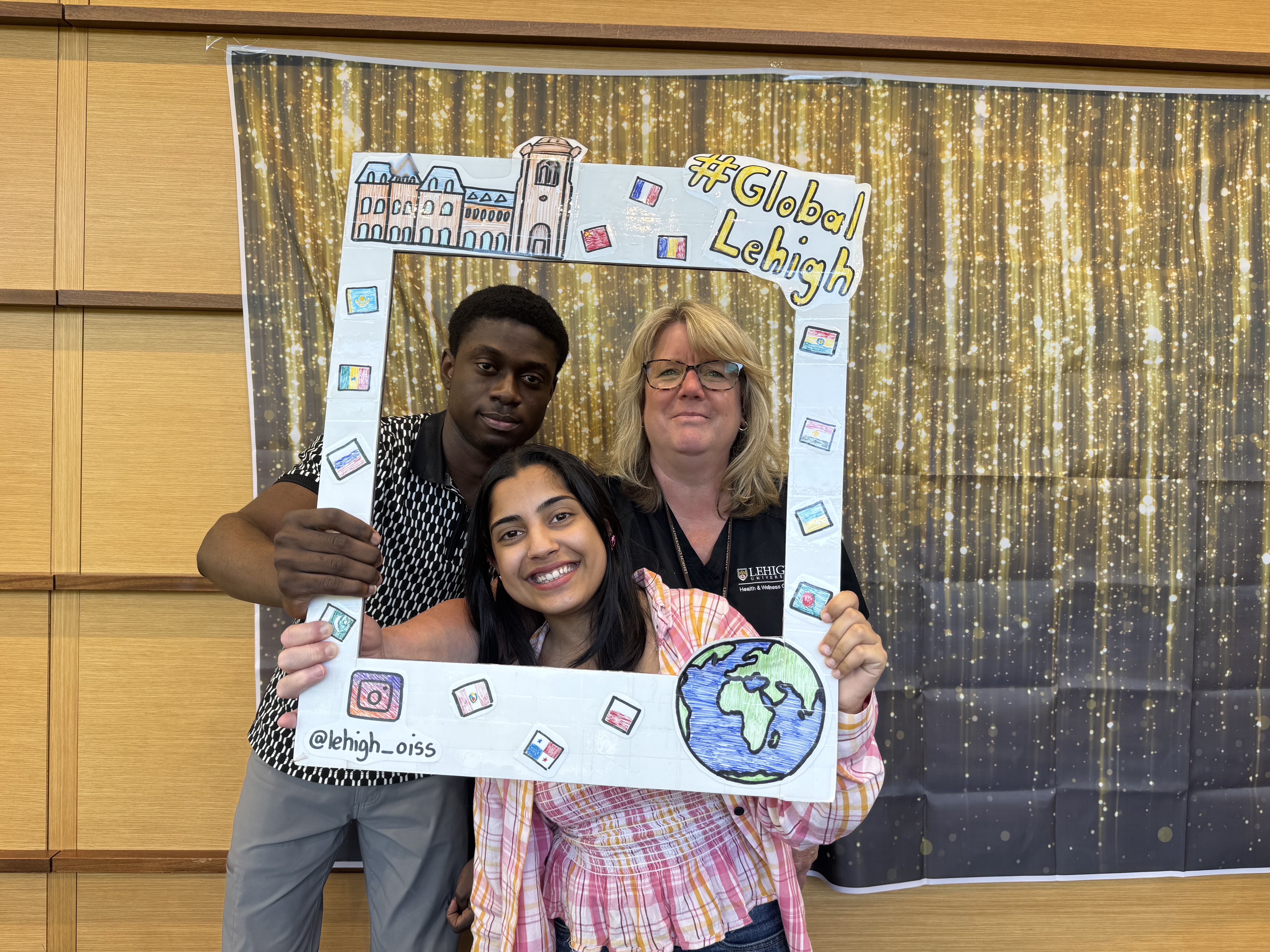 Three people posing with a Global Lehigh photograph display
