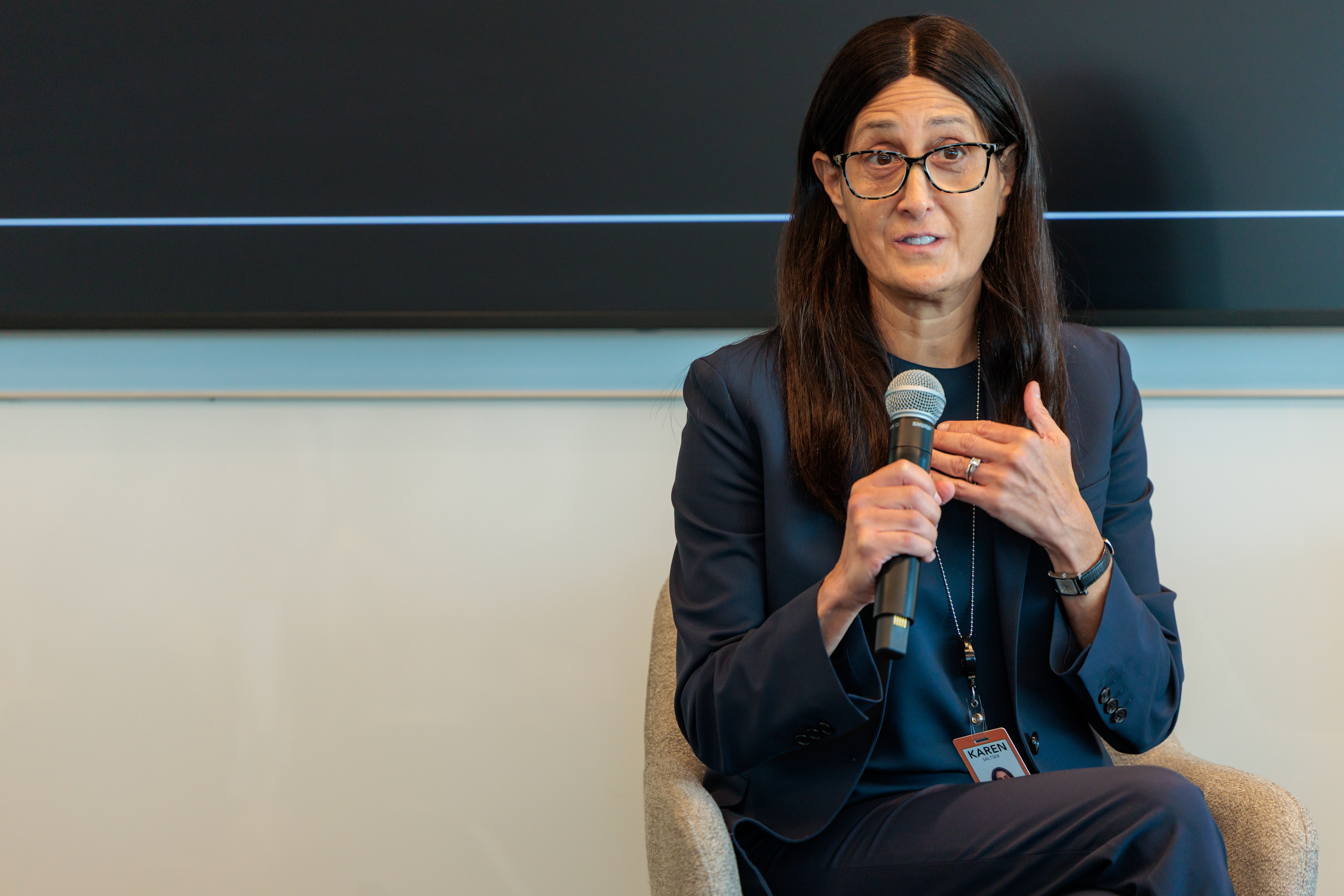 A woman speaking into a microphone while seated