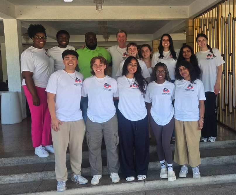 A group of college students posing for a photo outside a school