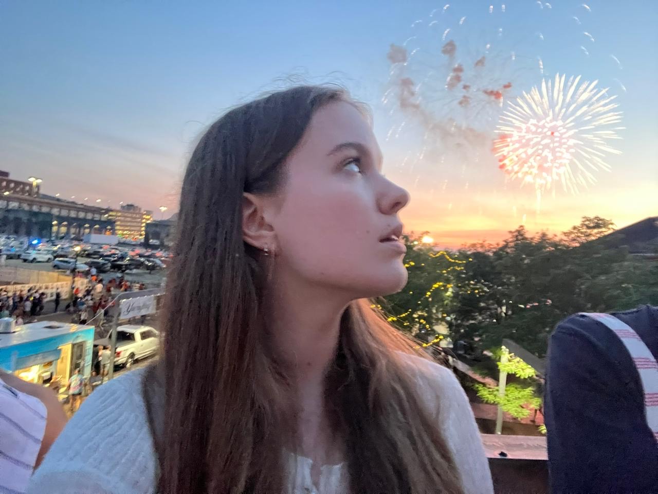 A young woman looks at fireworks outside