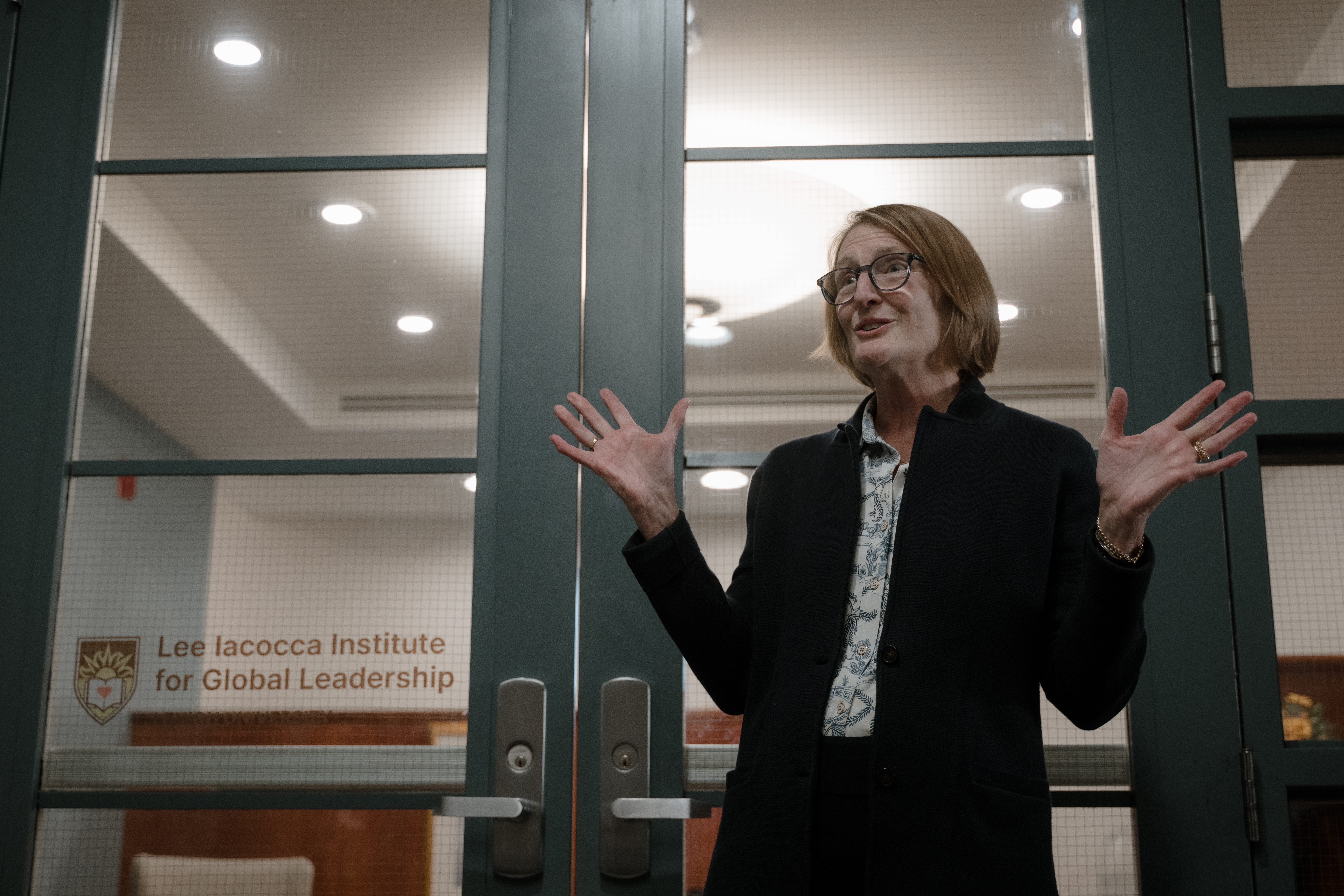 A woman speaking in front of a set of glass doors