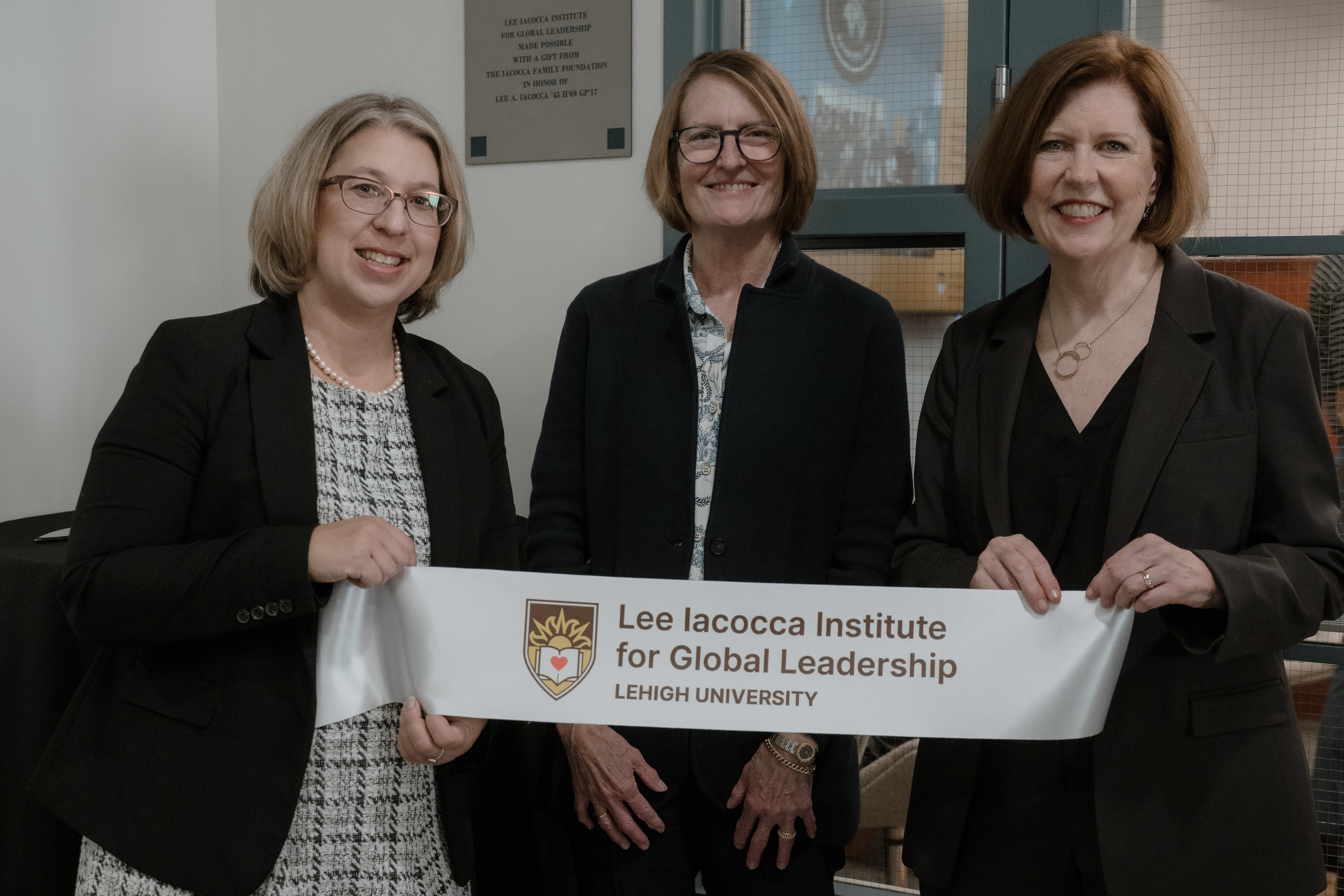 Three women standing with a ribbon at a ribbon-cutting event