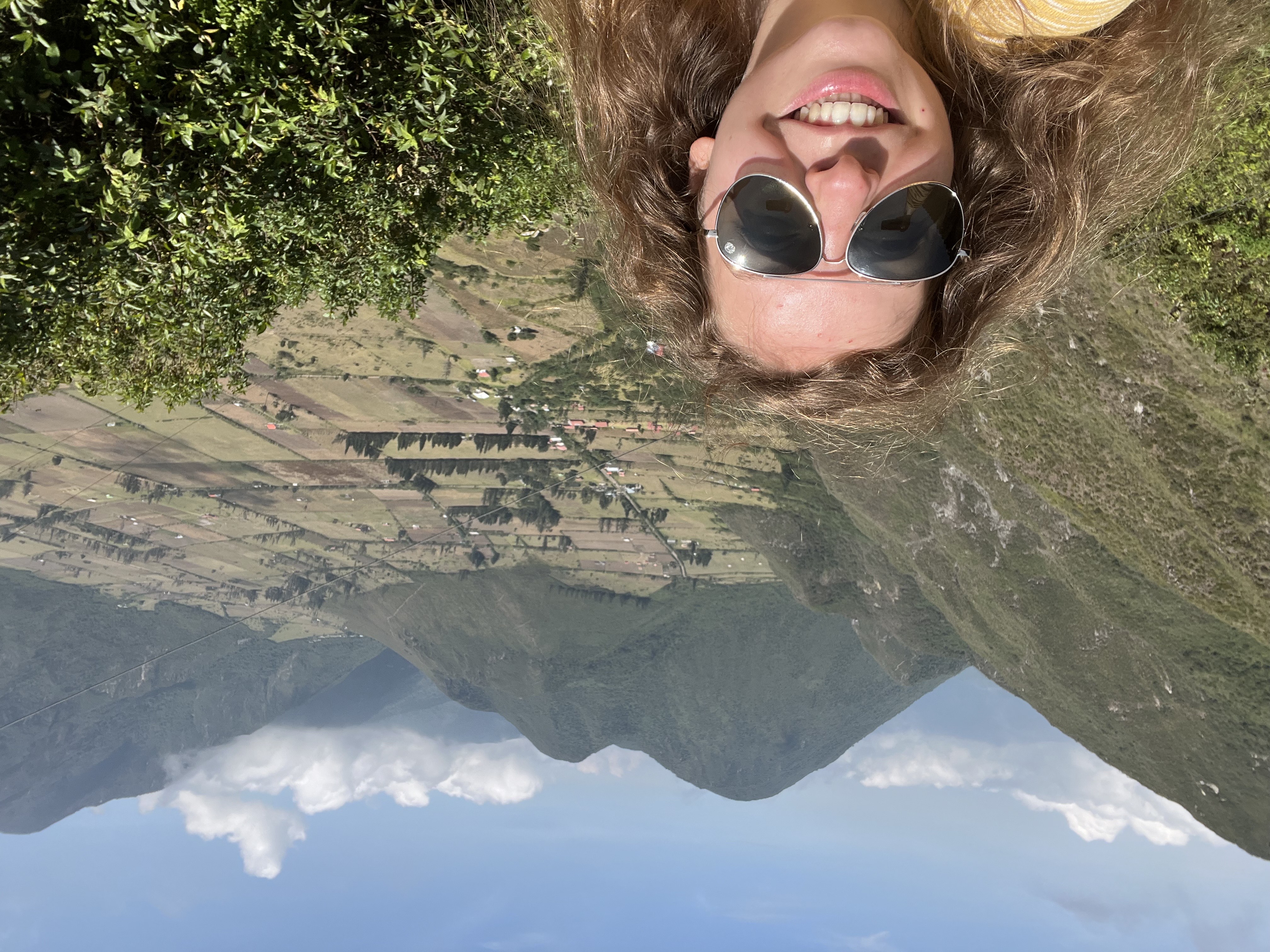 Liz Matthews taking a selfie with mountains and grassy terrain behind her