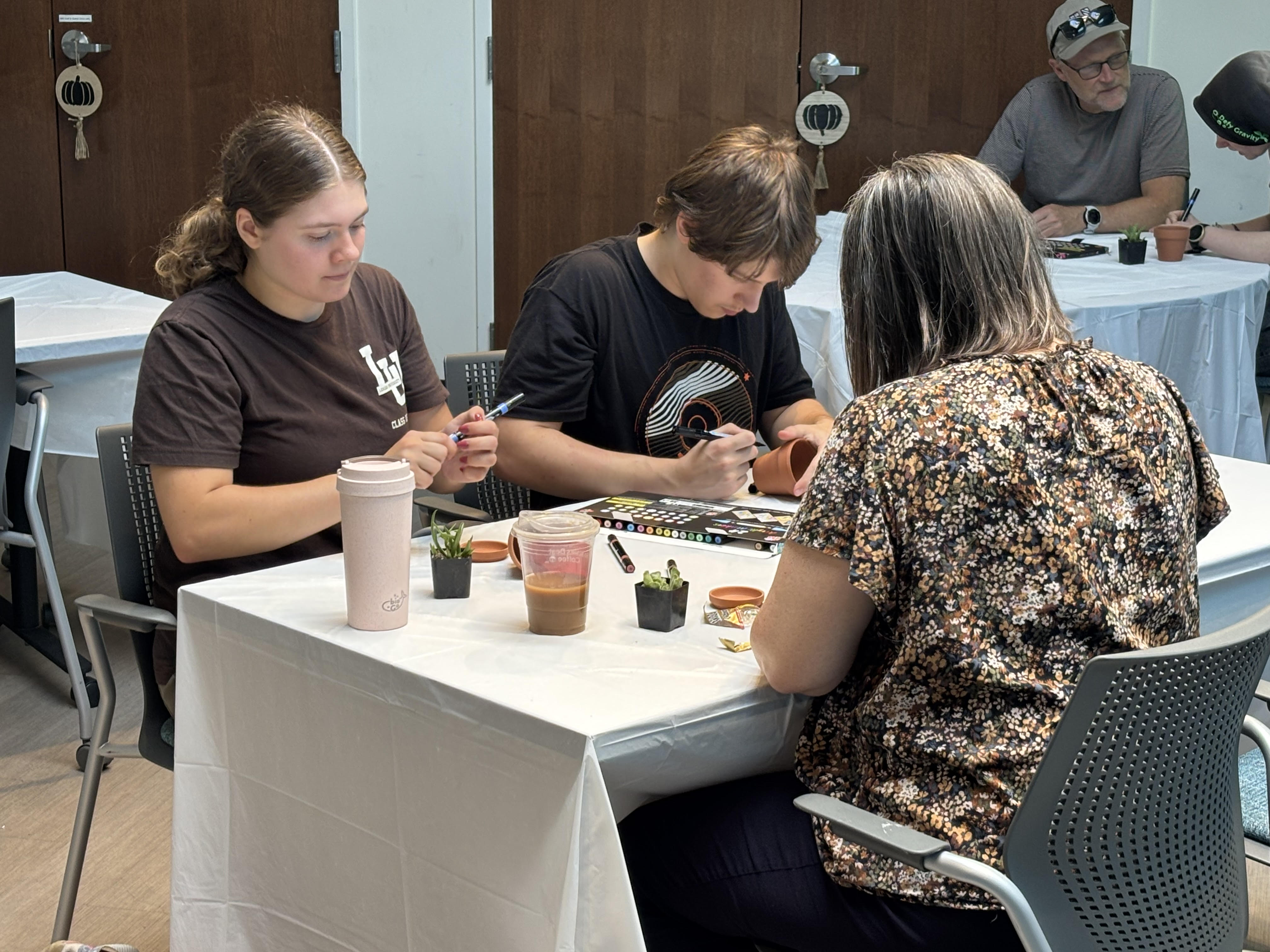 A family of three sitting at a table decorating pots