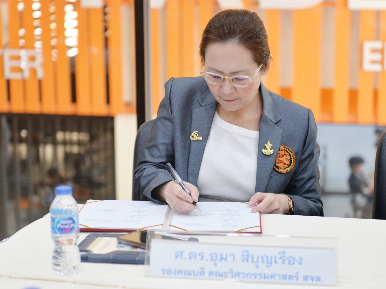 A woman signing a piece of paper while sitting at a table
