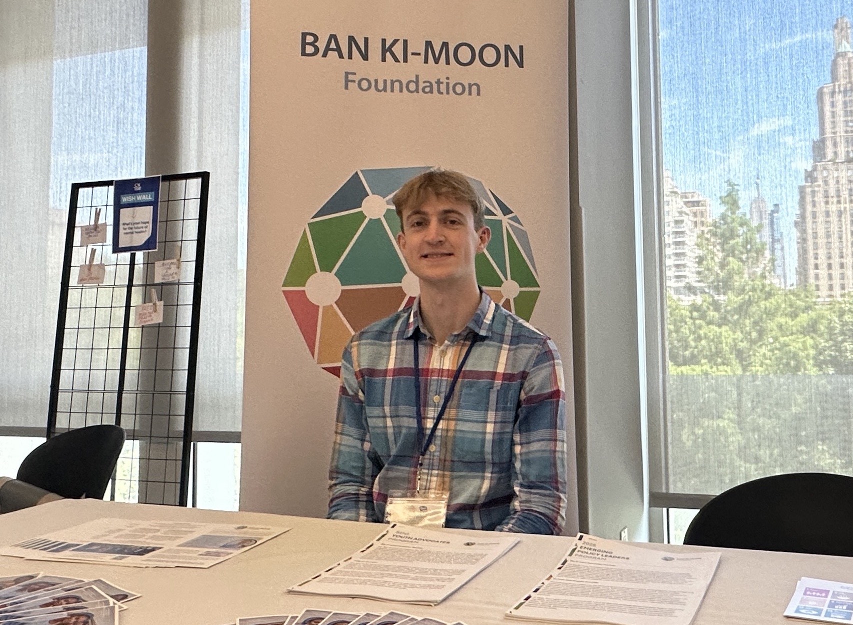 A young man sitting at a table in front of a Ban Ki-Moon Foundation banner