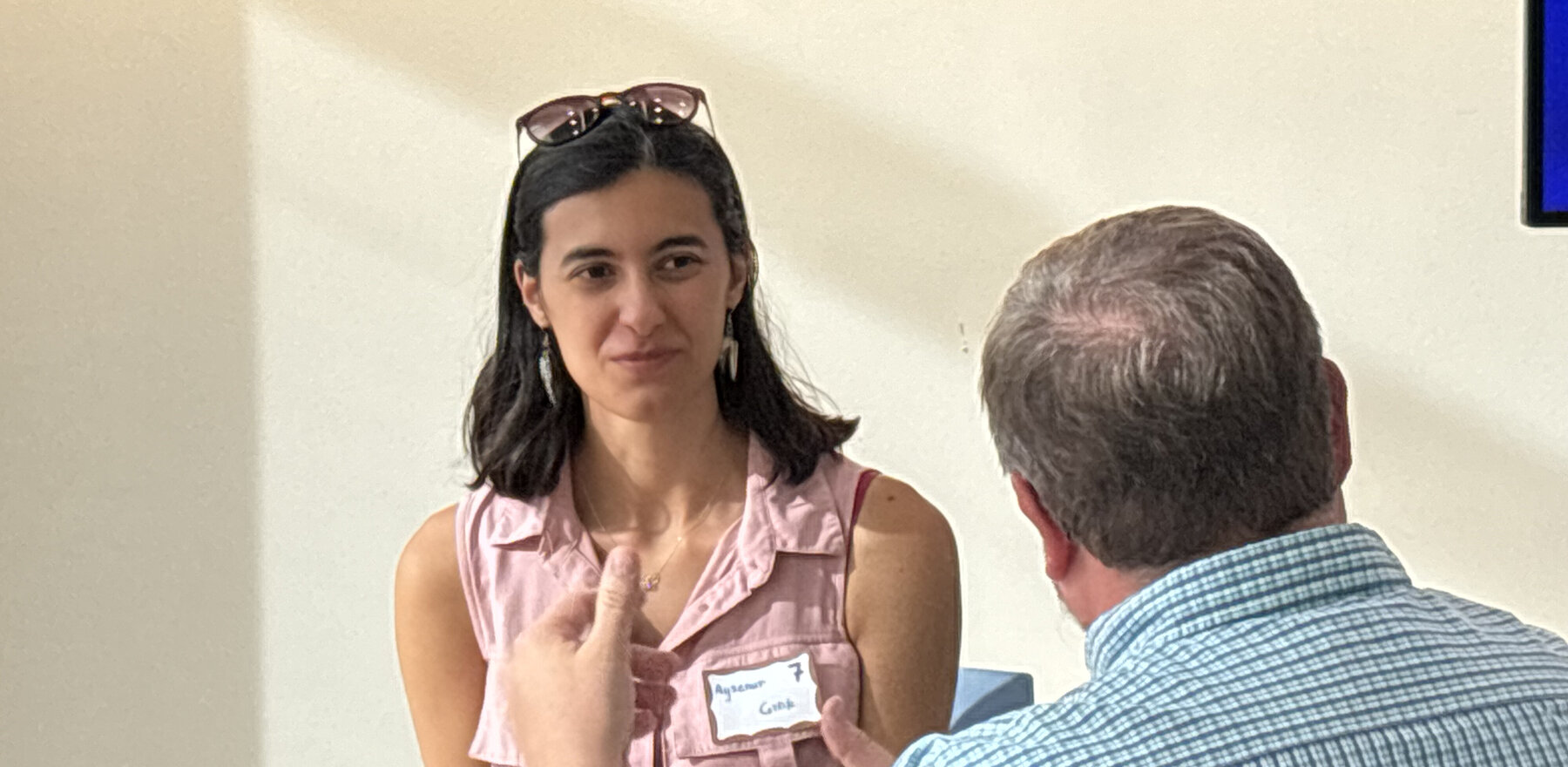 A young woman listening to a man speak while they are seated at a table