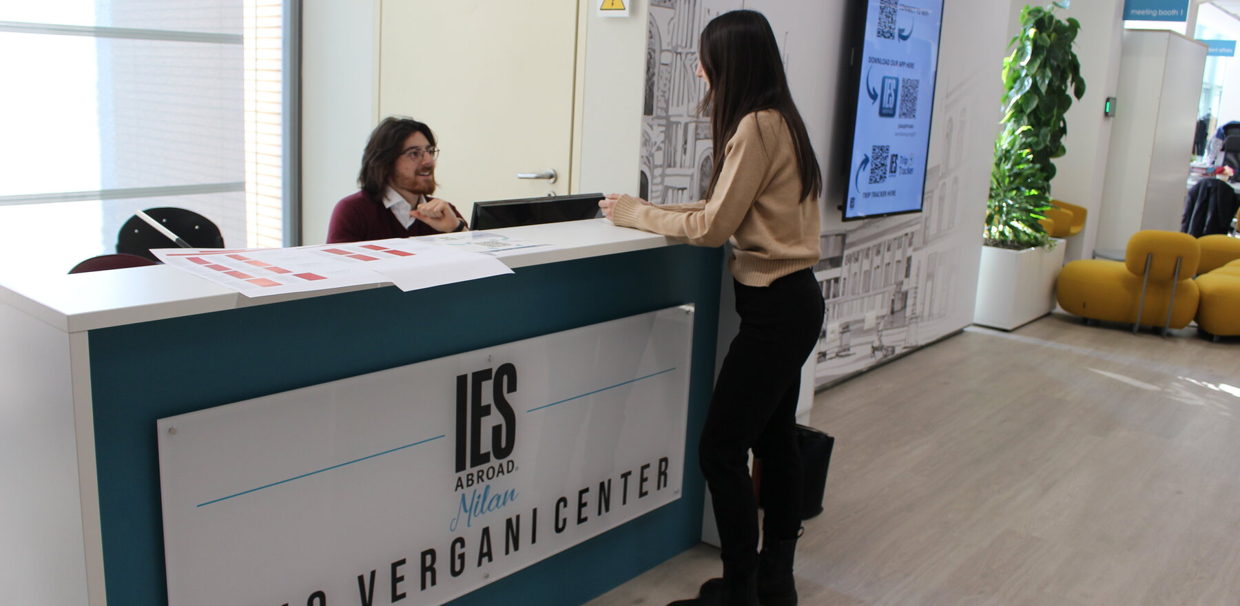 A woman speaking to a man seated at an IES Abroad desk