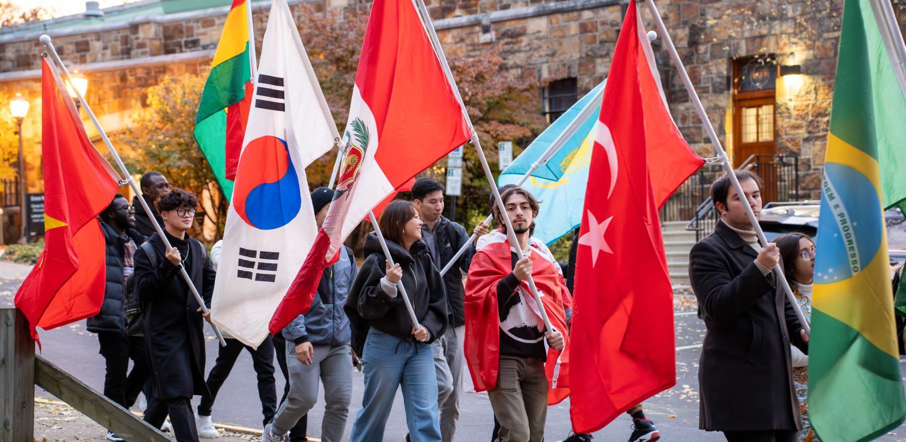 Students carrying various flags while walking in a parade on the campus of Lehigh University