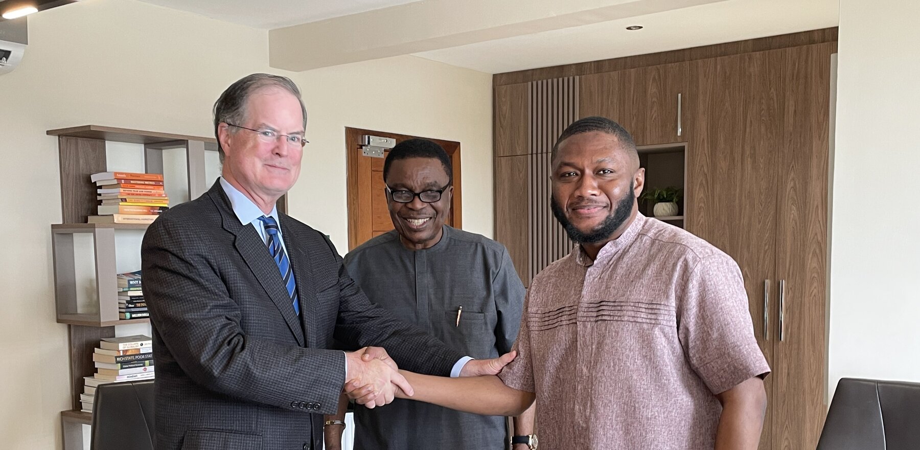 A man shaking hands with another man while they smile for the camera