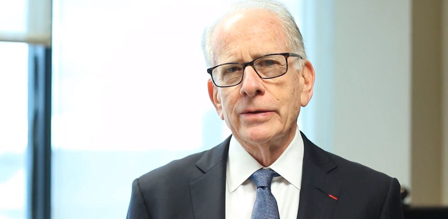 A photo of Allan Goodman wearing a suit and glasses