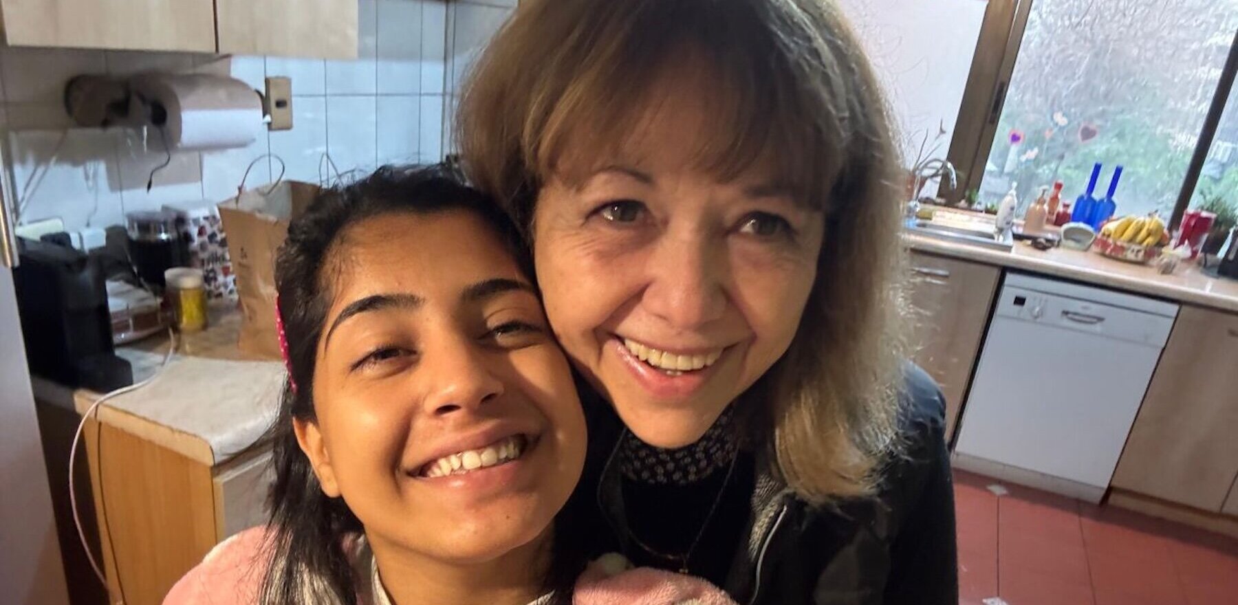 A young woman and older woman in a kitchen smiling for a selfie