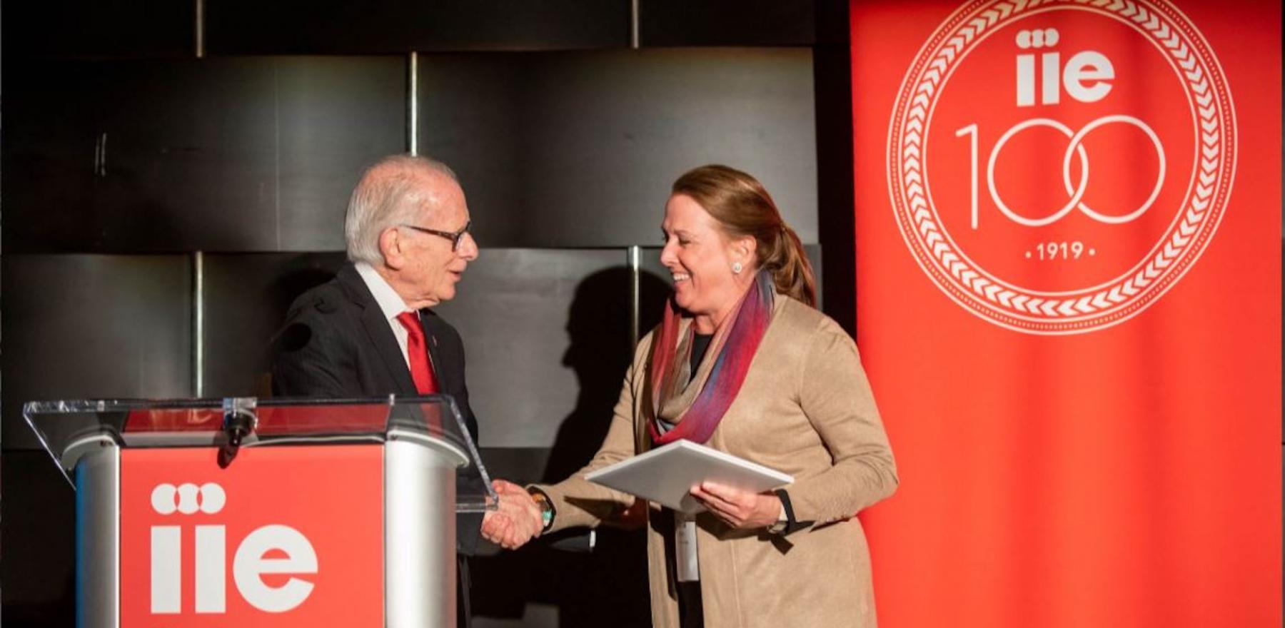 Carol Strange shaking hands at a podium with Allan Goodman, CEO of the Institute of International Education