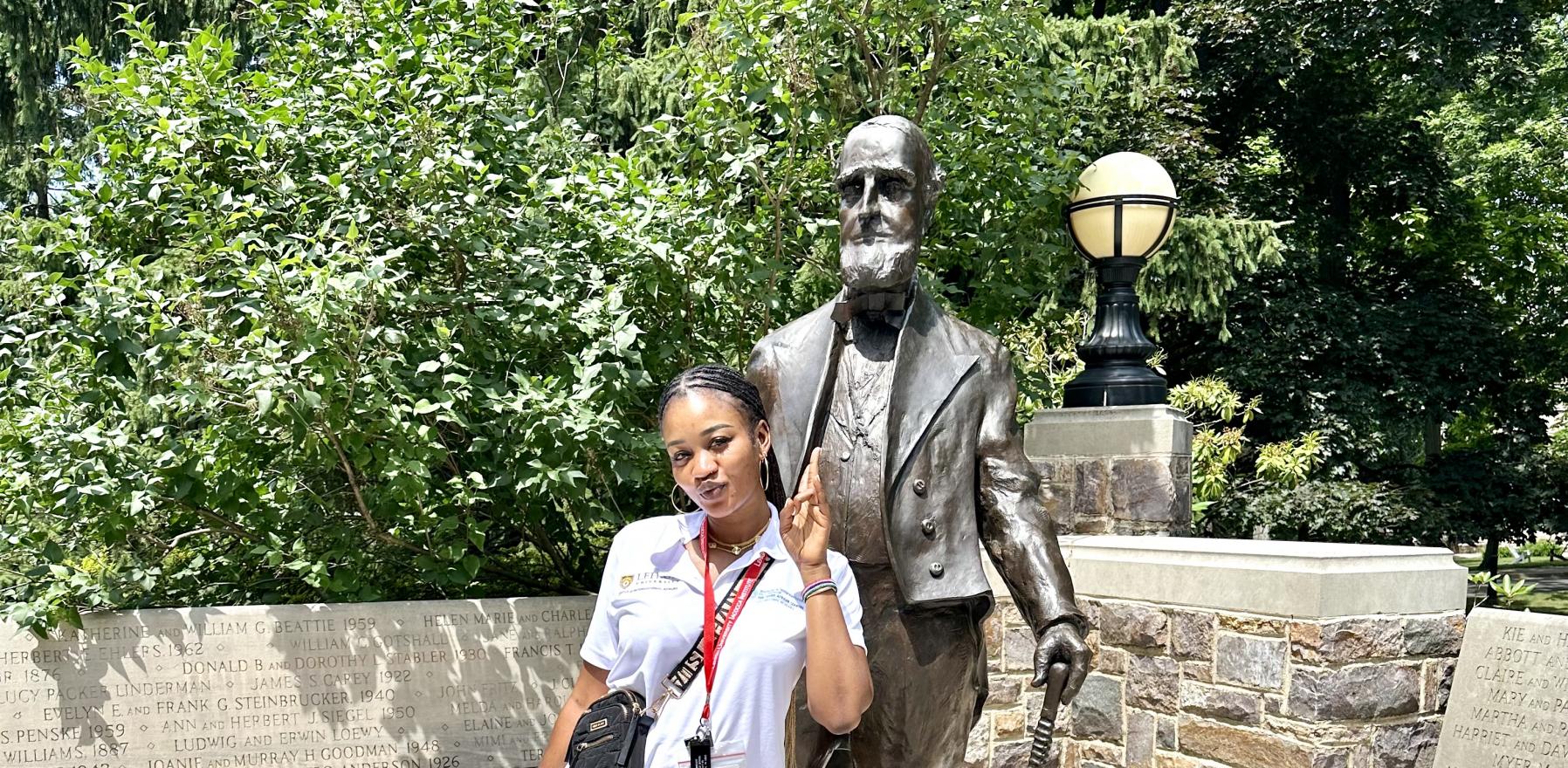 Cham Mendy in front of a statue of Asa Packer at Lehigh University