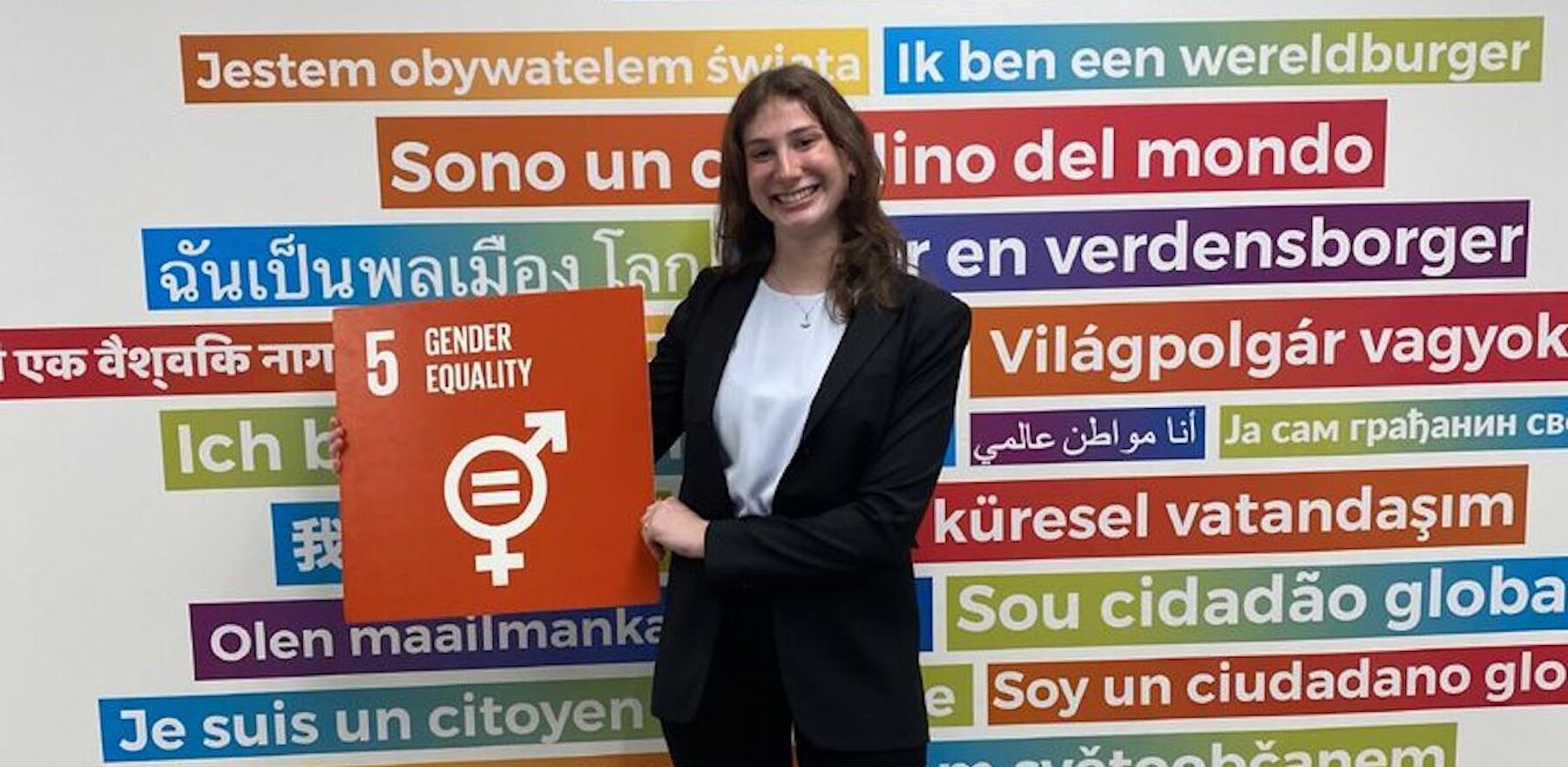 Claire Kirshenbaum standing in front of a wall with several sentences in different languages