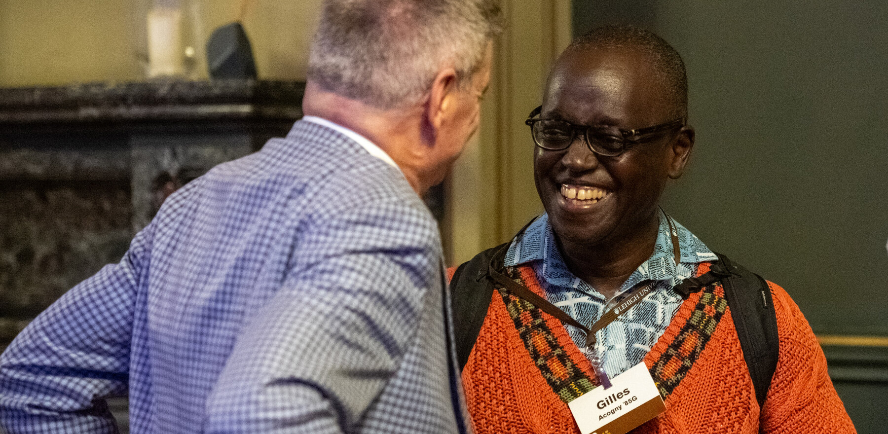 Gilles Acogny laughing while speaking to a man at a networking event