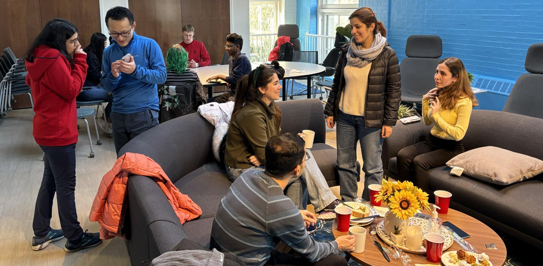 Several students in a lounge, speaking to each other and smiling