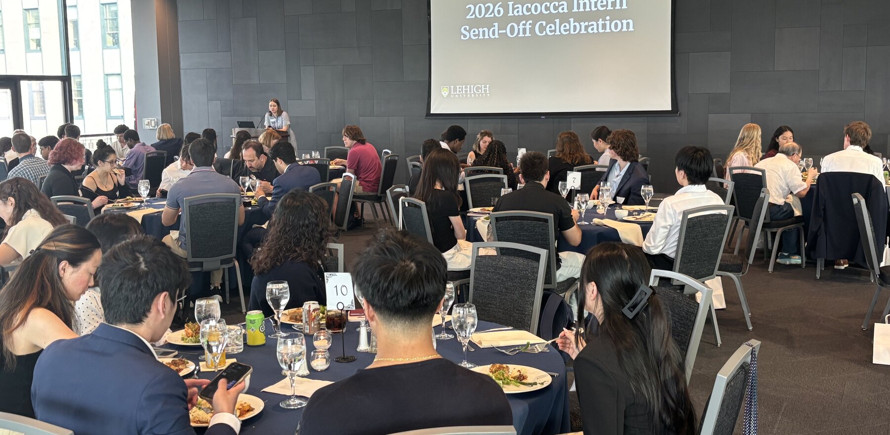 A group of people eating dinner at tables in a large conference room