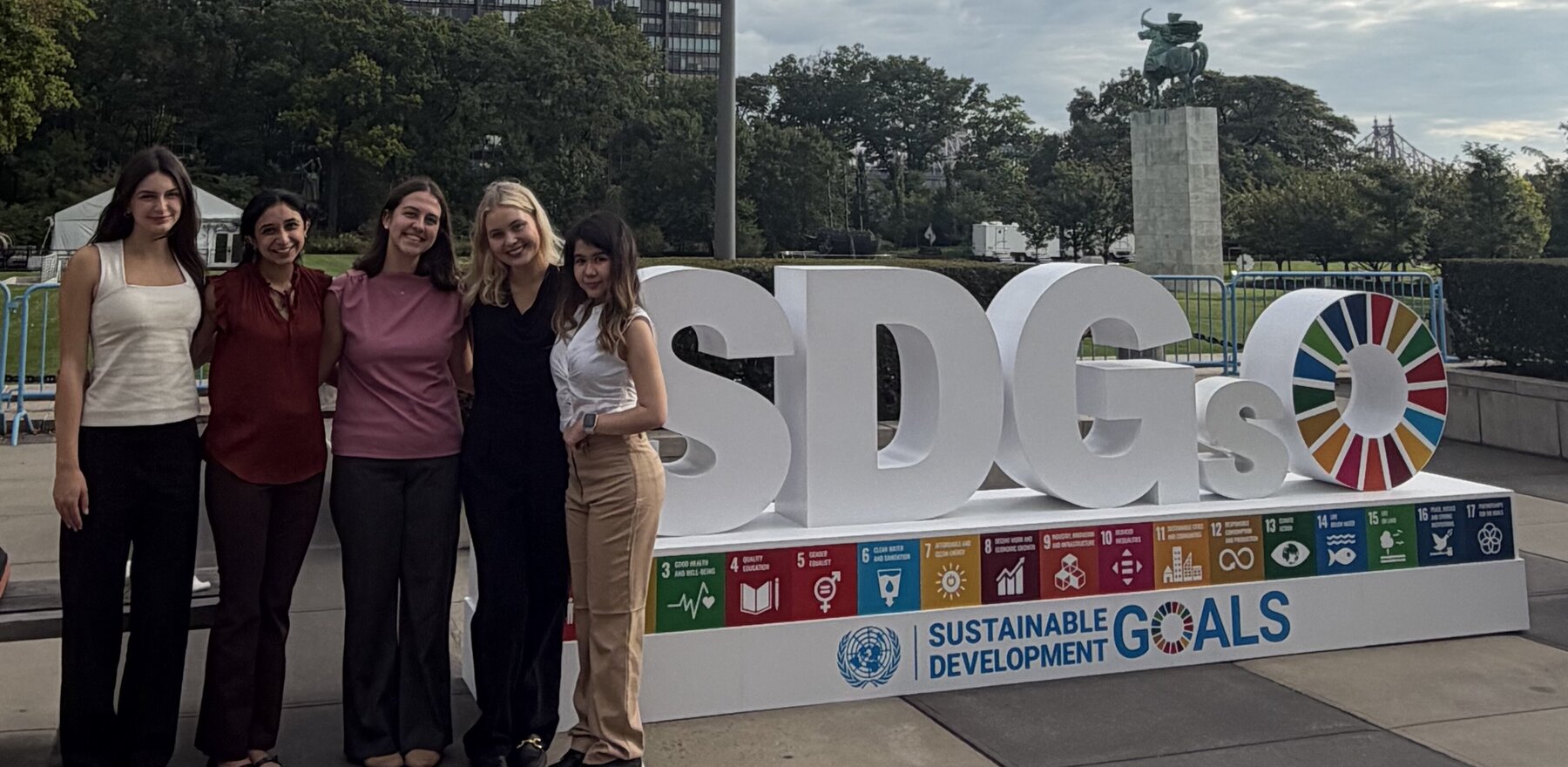 A group of people standing in front of a sign that says SDGs