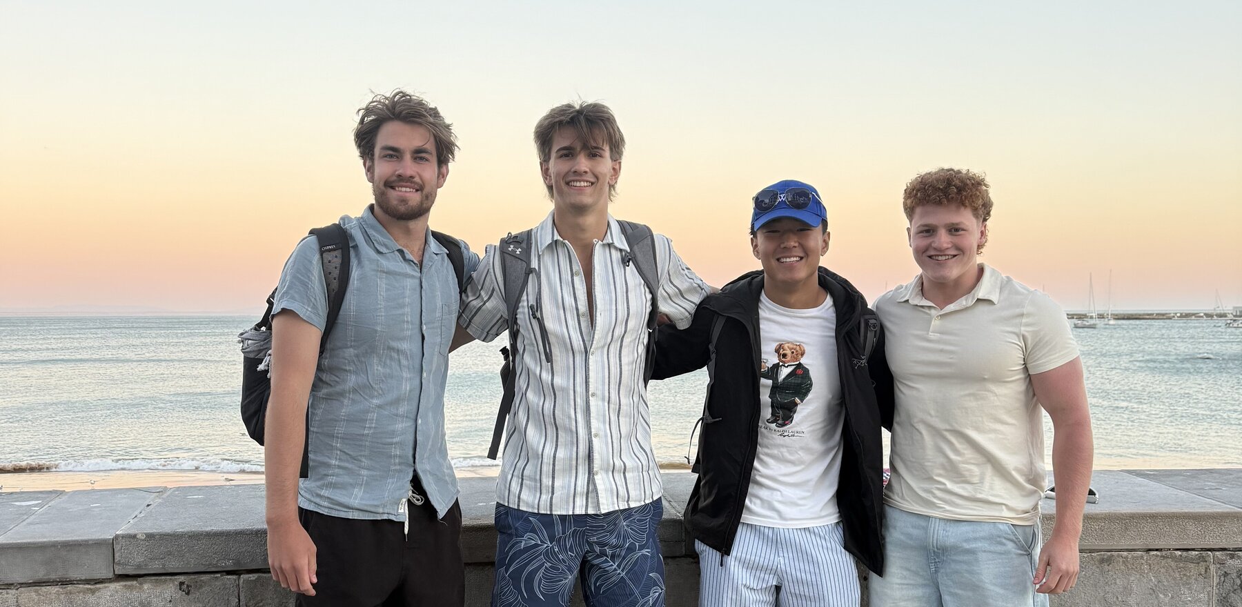 A group of four young men standing in front of a sunrise