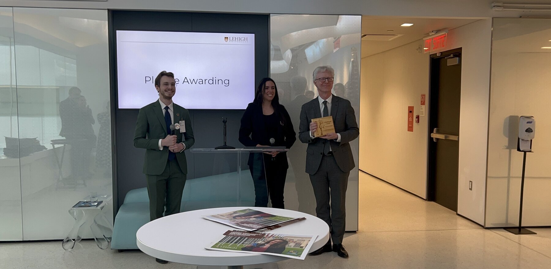 Three people standing in front of a screen and posing for a photo