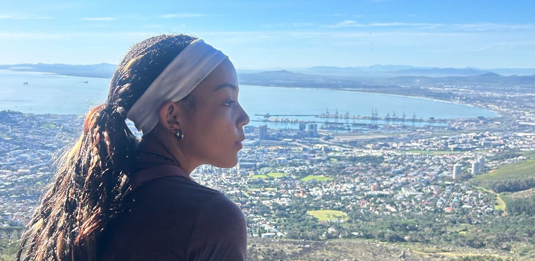 A young woman sitting and looking out at a landscape horizon